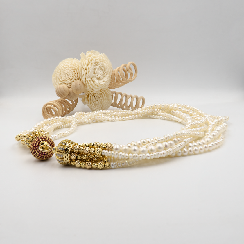 עיצוב אלגנטי עם פנינים טבעיות וסוגר בעיצוב ייחודי. כל שורת פנינים מוסיפה לתכשיט מימד של תנועה, עומק ויוקרה קלאסית – יחד הן יוצרות נשיות עוצמתית עם איזון עדין. הברק הטבעי של הפנינים משתלב עם האלמנטים המוזהבים לרושם אלגנטי עם טוויסט עכשווי. הסוגר הייחודי, המעוטר באבני קריסטל קטנות בגוון יין עמוק, מהווה מוקד עיצובי שמוסיף עניין ותחושת פאר. שרשרת אידאלית לאירוע חגיגי, חתונה או ערב חשוב – אביזר מרכזי בלוק חגיגי ונשי.