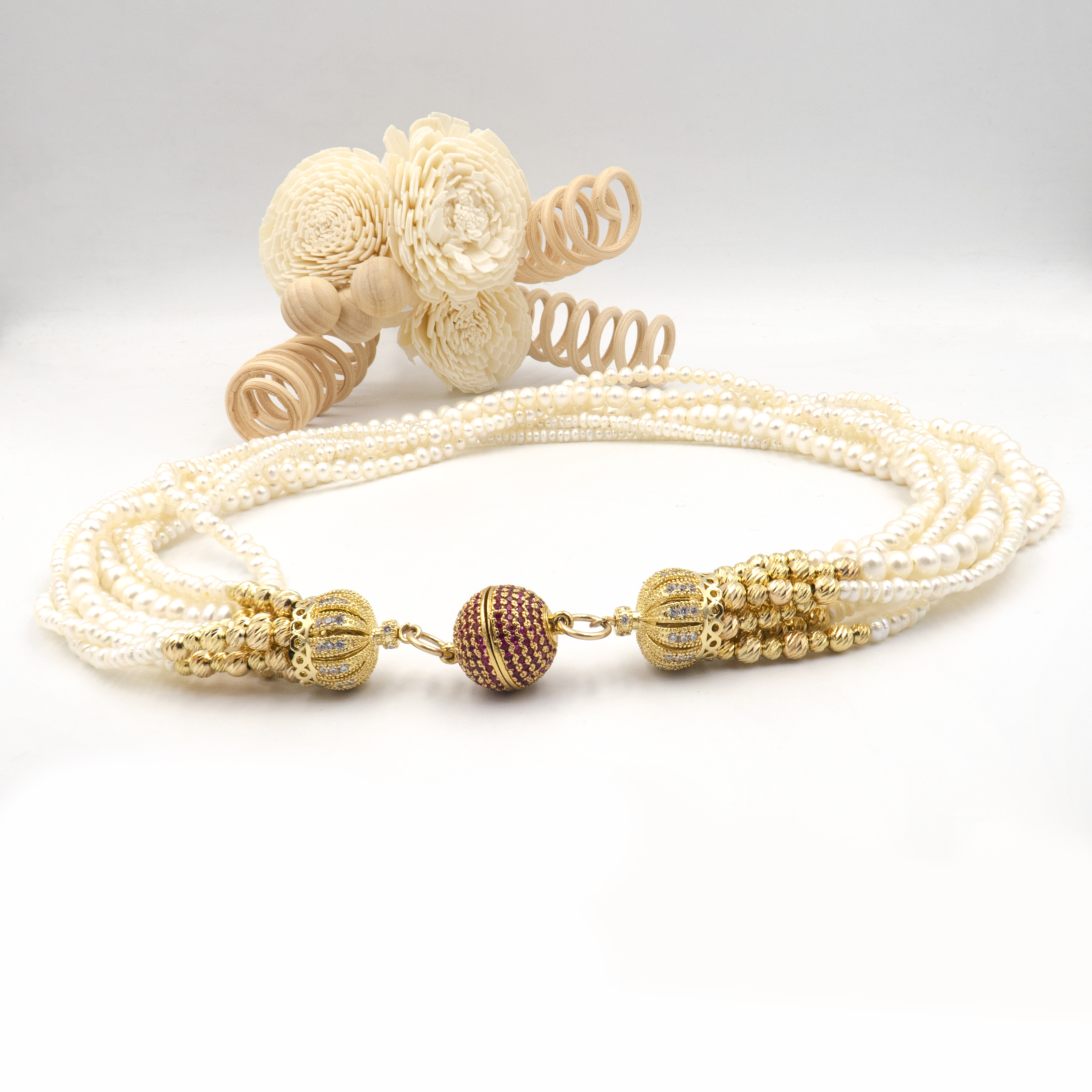 עיצוב אלגנטי עם פנינים טבעיות וסוגר בעיצוב ייחודי. כל שורת פנינים מוסיפה לתכשיט מימד של תנועה, עומק ויוקרה קלאסית – יחד הן יוצרות מראה דרמטי עם רוך נשי. הברק הטבעי של הפנינים משתלב עם האלמנטים המוזהבים לתחושת יוקרה על־זמנית. הסוגר הייחודי, המעוטר באבני קריסטל קטנות בגוון יין עמוק, מהווה מוקד עיצובי שמוסיף עניין ותחושת פאר. שרשרת אידאלית לאירוע חגיגי, חתונה או ערב חשוב – אביזר מרכזי בלוק חגיגי ונשי.