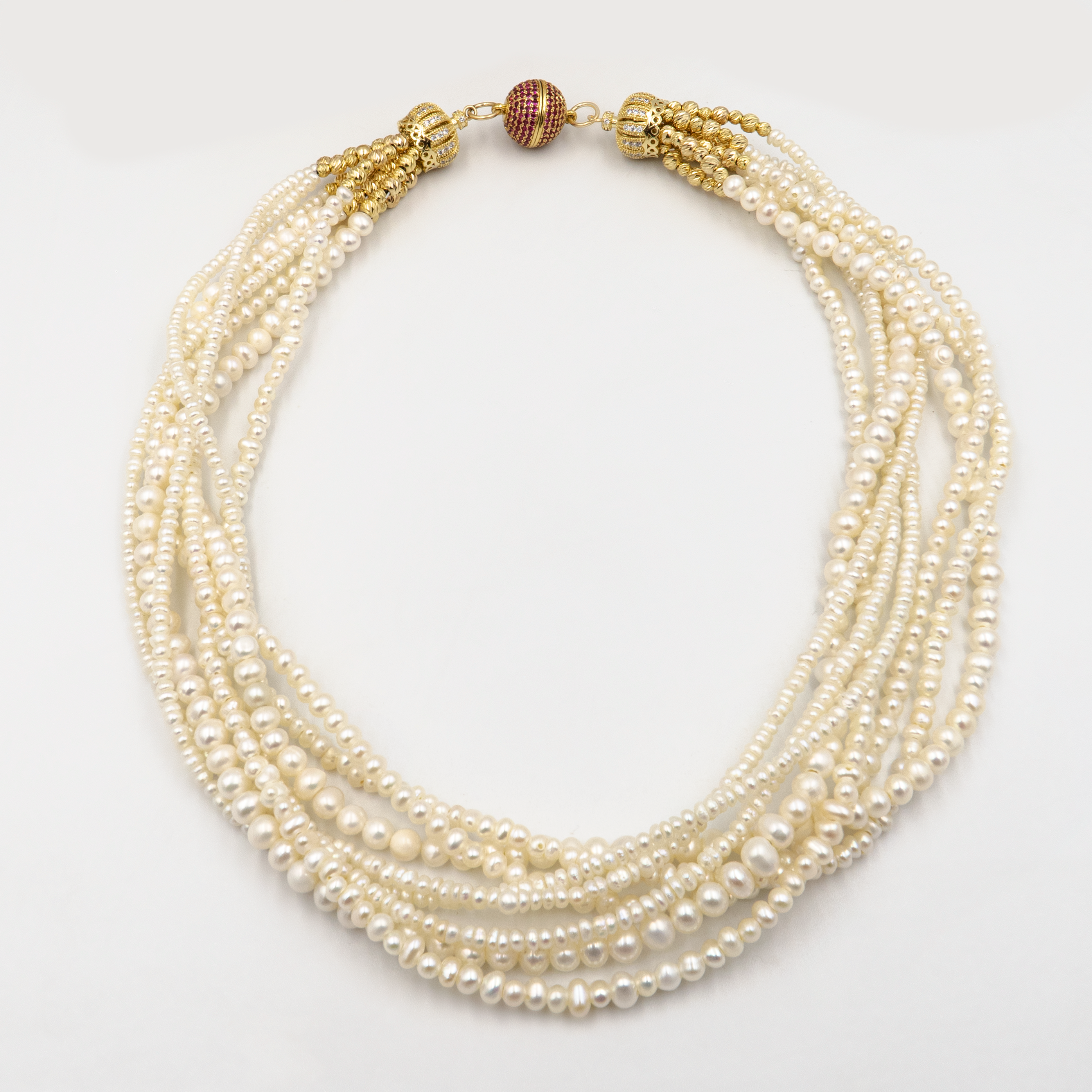 תכשיט מרשים בעבודת יד עם שורות פנינים ונגיעות זהובות. כל שורת פנינים מוסיפה לתכשיט מימד של תנועה, עומק ויוקרה קלאסית – יחד הן יוצרות מראה דרמטי עם רוך נשי. הברק הטבעי של הפנינים משתלב עם האלמנטים המוזהבים לתחושת יוקרה על־זמנית. הסוגר הייחודי, המעוטר באבני קריסטל קטנות בגוון יין עמוק, מהווה מוקד עיצובי שמוסיף עניין ותחושת פאר. שרשרת אידאלית לאירוע חגיגי, חתונה או ערב חשוב – פריט שמושך מבטים ומייצר אמירה.