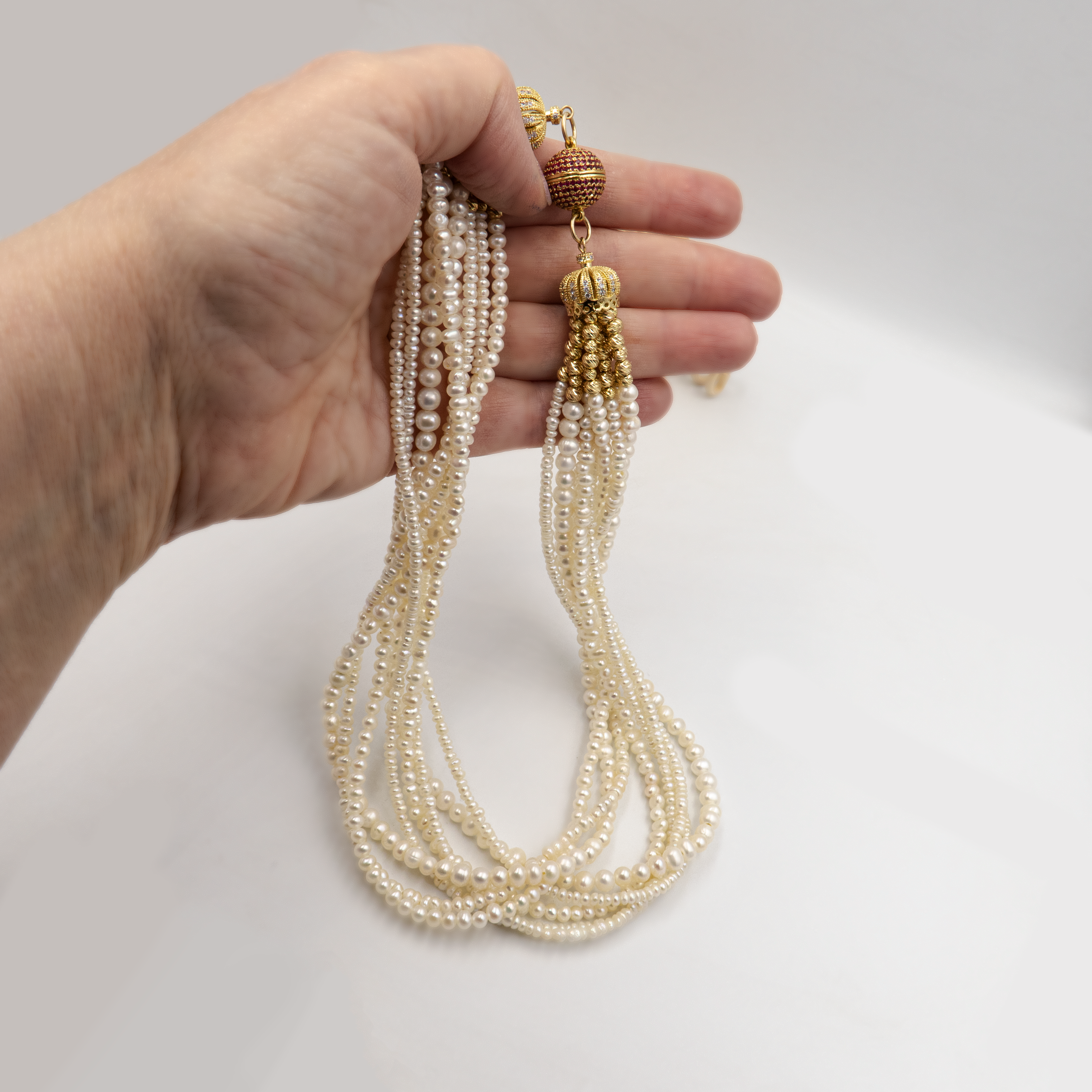 תכשיט מרשים בעבודת יד עם שורות פנינים ונגיעות זהובות. כל שורת פנינים מוסיפה לתכשיט מימד של תנועה, עומק ויוקרה קלאסית – יחד הן יוצרות סטייל חגיגי עם מראה קלאסי. הברק הטבעי של הפנינים משתלב עם האלמנטים המוזהבים לרושם אלגנטי עם טוויסט עכשווי. הסוגר הייחודי, המעוטר באבני קריסטל קטנות בגוון יין עמוק, מהווה מוקד עיצובי שמוסיף עניין ותחושת פאר. שרשרת אידאלית לאירוע חגיגי, חתונה או ערב חשוב – פריט שמושך מבטים ומייצר אמירה.