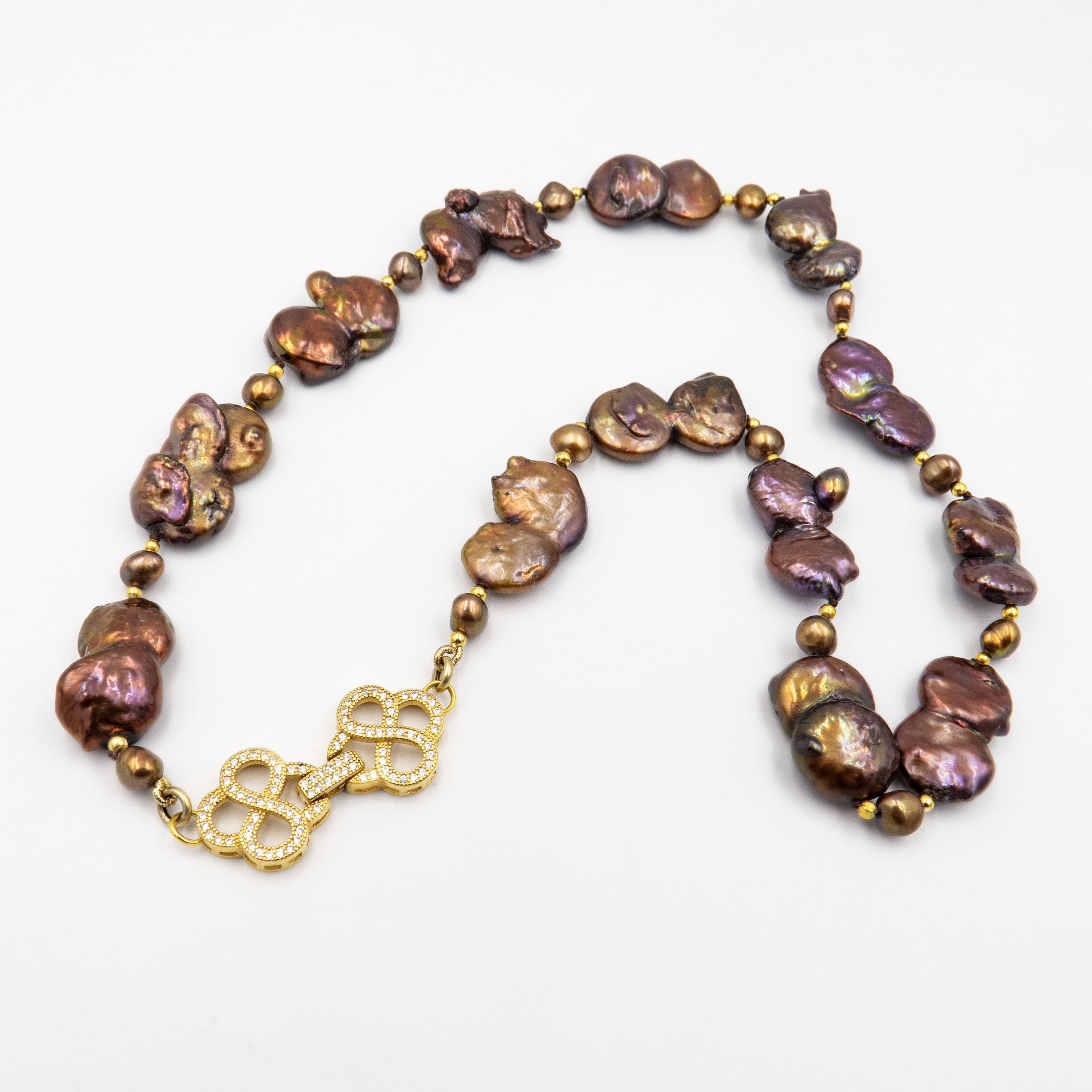 פריט בעיצוב לא שגרתי, מלא נוכחות המורכבת מפניני בארוק טבעיות בגוון שוקולד עמוק, עם אביזרים בציפוי זהב שמדגישים את צורתן הבלתי אחידה והמרקם החי של כל פנינה. הברק המטאלי החם של הפנינים משתלב באופן הרמוני עם הנגיעות המוזהבות, ויוצר ניחוח של טבע פראי ואלגנטי יחד. שילוב קלאסי ונועז כאחד – אידיאלי לאירוע ערב, להופעה עם אמירה או כמתנה מרשימה לאישה מיוחדת. פניני הבארוק, כל אחת עם אישיות משלה, הופכות את השרשרת הזו לשרשרת שלא דומה לשום דבר אחר – טבעית, אותנטית ומרשימה.