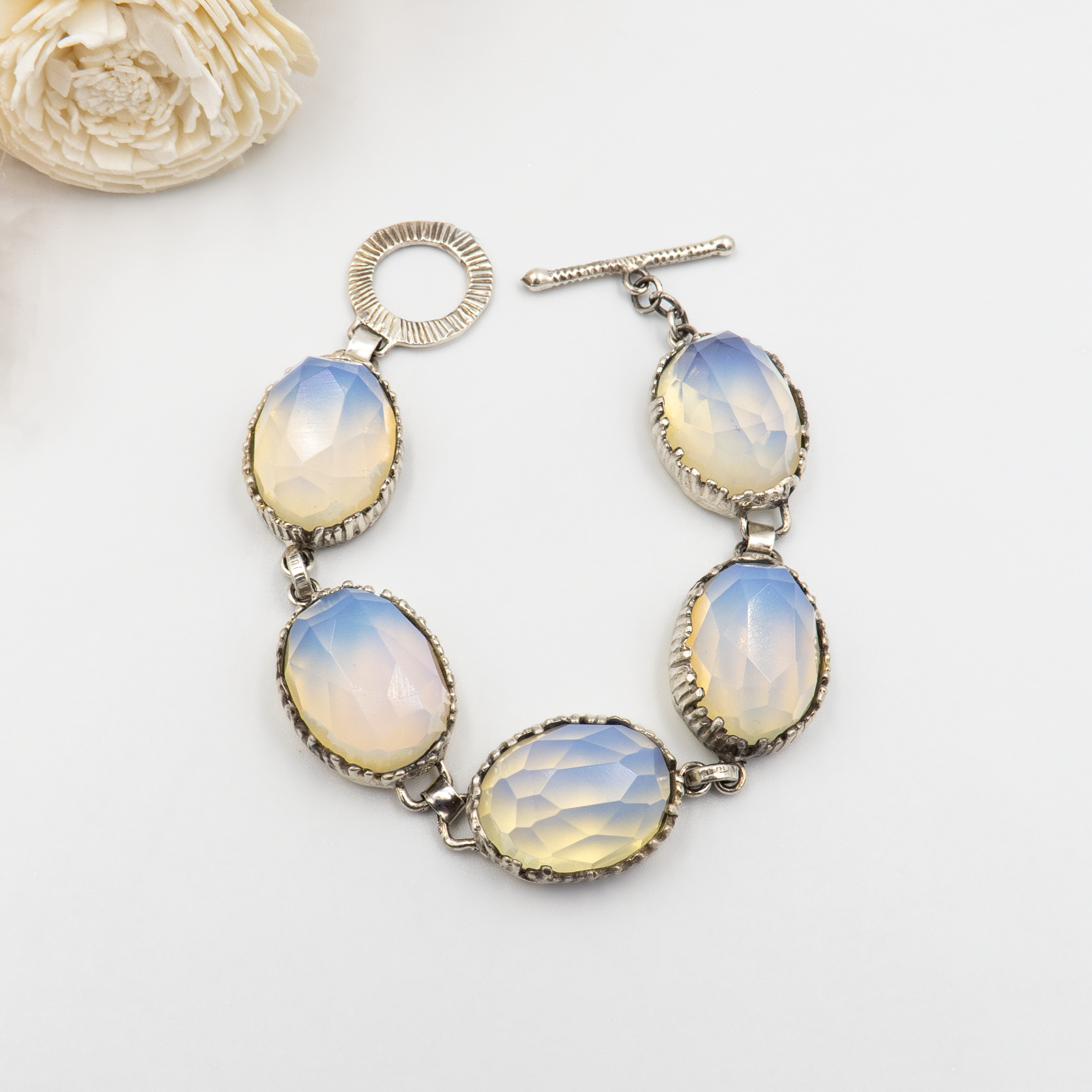 צמיד כסף סטרלינג בעבודת יד, בעל חמש אבני אופליט בגוון אופל שמיימי – תערובת עדינה של תכלת, לבן ושמנת. סוגר טי דקורטיבי מעניק גימור אלגנטי וקל לשימוש. צמיד ייחודי ונשי שמתאים לאירועים חגיגיים כמו חתונה, בר מצווה או חג, וגם לשימוש יומיומי עם טוויסט אלגנטי. תכשיט עם מראה אל-זמני ורוך מרגש.

