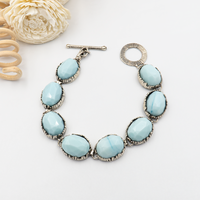 צמיד כסף מעוצב עם אבן אופליט כחולה-לבנה, בגימור פאות מלוטש המשקף אור ומעניק מראה זוהר. הצבעים משתנים בין תכלת, קרח ולבן חלבי, מה שהופך כל תכשיט לייחודי. מתאים לנשים שאוהבות עיצוב שקט עם עומק וקסם פנימי.

