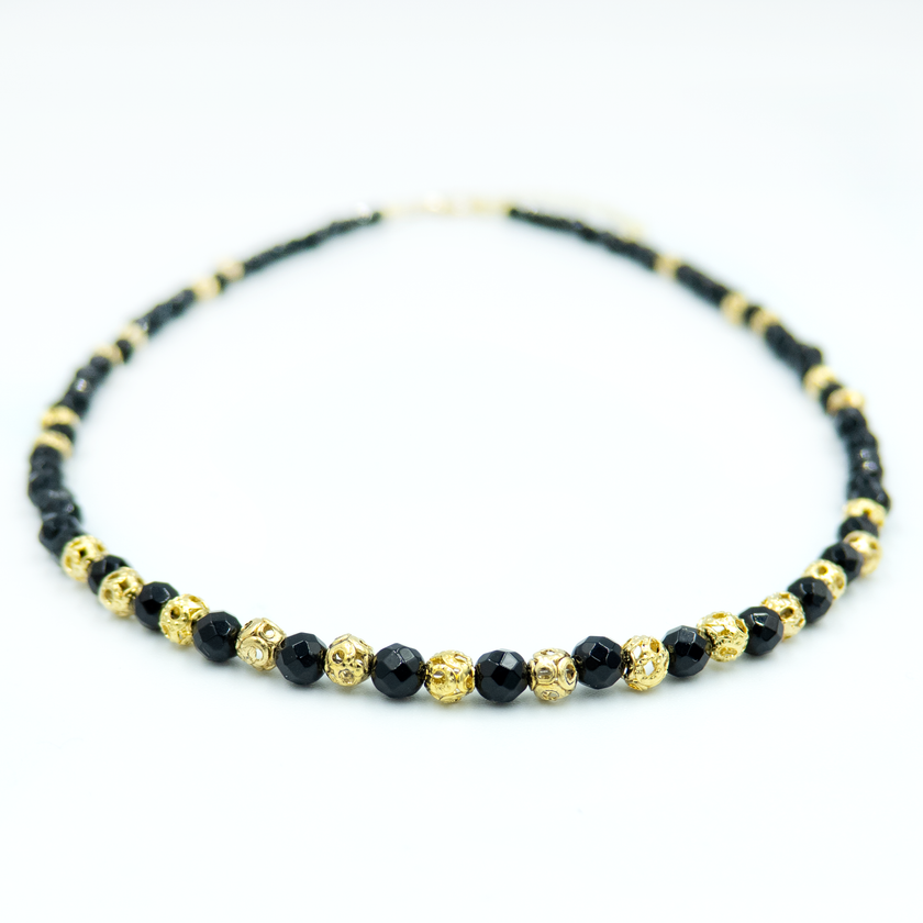 תכשיט שמשדר עוצמה עדינה – שרשרת עם אבני אוניקס בגוון שחור מלוטש, בעלות ברק טבעי ומרקם אחיד, יחד עם אלמנטים מצופי זהב בעיצוב מודרני. השרשרת מתאימה לנשים שמחפשות שילוב בין קלאסי לאורבני, בין חומר טבעי לגימור יוקרתי. האבנים בנויות בצורה סימטרית שנותנת תחושת איזון ודיוק, והזהב מוסיף תחושת חמימות ונשיות. אידיאלי לכל מי שמחפשת אקססורי עם נוכחות אבל לא צורח – אלא פשוט מדבר אל מי שצריך להקשיב.

