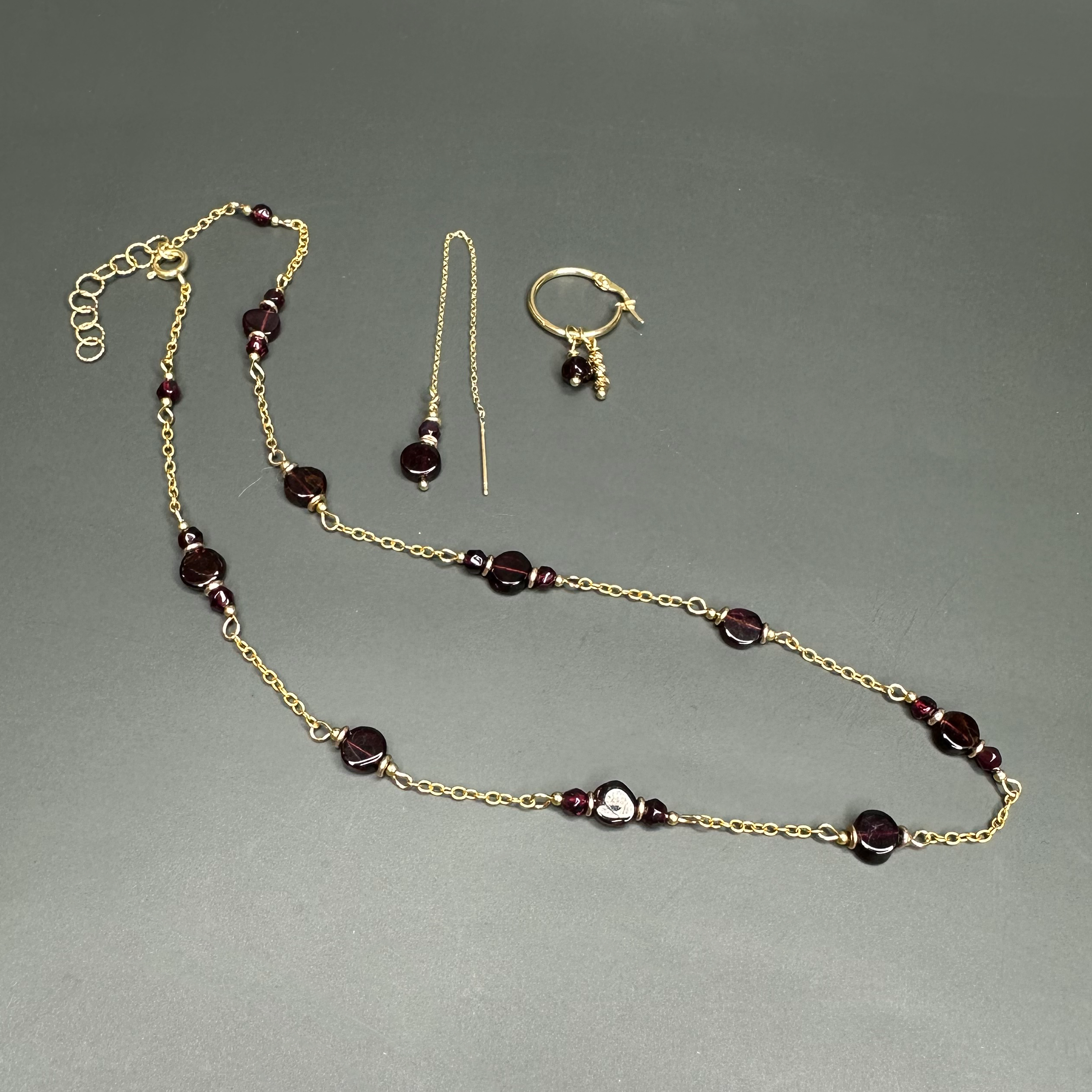 סט תכשיטים אלגנטי בסגנון קלאסי – שרשרת זהב 14 קראט עם תליון גארנט אדום עז, לצד עגילים בעיצוב עדין להמחשה בלבד.

ואפשרות נוספת עם ניחוח יוקרתי יותר:

שרשרת זהב 14 קראט יוקרתית עם אבן גארנט מרשימה, מוצגת באווירה אלגנטית לצד עגילים תואמים להמחשה בלבד.