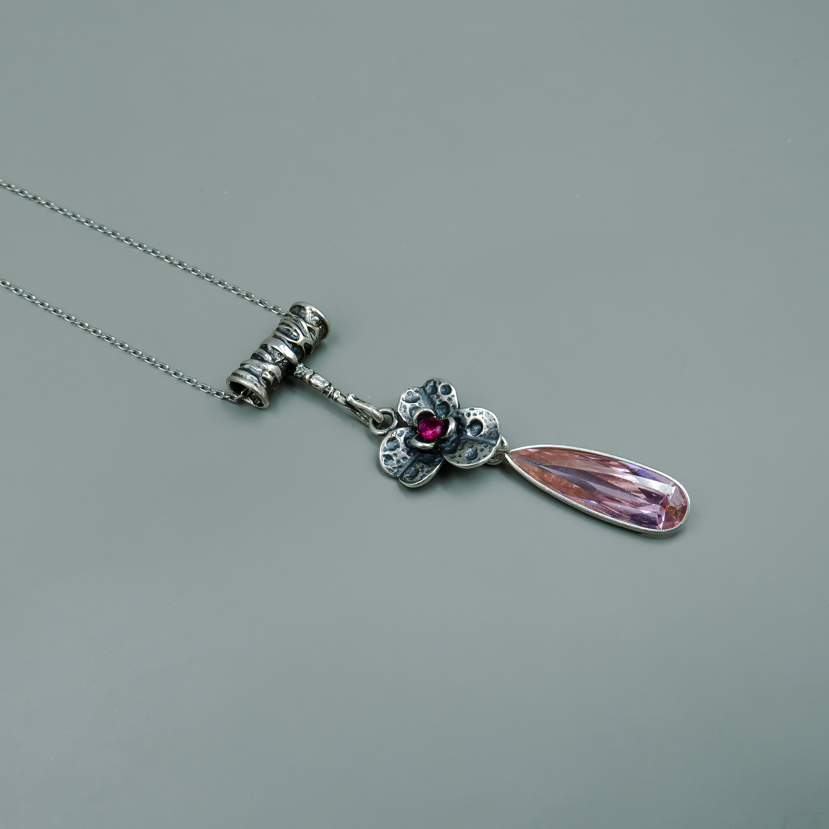 שרשרת עדינה עם תליון בסגנון פיוטי, עשויה כסף ומשולבת באבן ורודה בגוון עמוק שממוקמת במרכזו של פרח מעוצב. סביב האבן פרטי חריטה עדינים בעלי מראה טבעי. טיפה ארוכה ומבריקה בגוון ורדרד משתלשלת מהפרח ויוצרת תנועה אלגנטית. זהו תכשיט שמזמין מבט נוסף – שילוב בין רכות לעוצמה, בין עדינות לפרטים מרשימים. מתאים לנשים שמעריכות עיצוב ייחודי ואיכותי, אוהבות פריטים עם אמירה אישית וסטייל עדין עם קריצה דרמטית.

