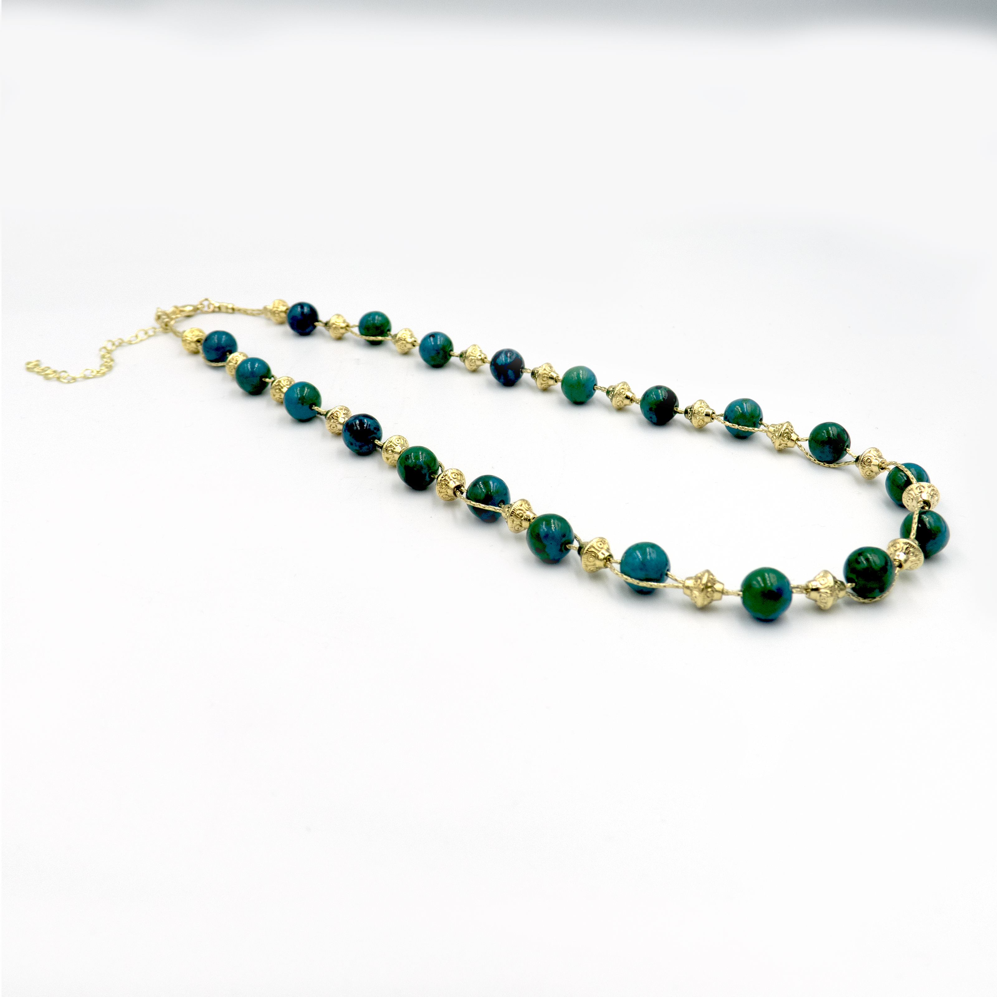 שרשרת עבודת יד מאבני כריסוקולה טבעיות בגווני טורקיז, ירוק וכחול עמוק – מפגש הרמוני בין גווני טבע עזים. כל אבן נבחרת בקפידה ומציגה דפוס ייחודי משלה, אין שתיים זהות – כל תכשיט מספר סיפור אחר. הכריסוקולה ידועה כאבן המוכרת בכוחות ההרגעה והחיזוק שלה, כזו שמחברת את הלובשת לאנרגיה פנימית של שקט וביטחון. העיצוב של השרשרת שומר על קו נקי ומוקפד, ומבליט את יופיין הגולמי של האבנים. מתאים למי שמחפשת תכשיט שמדבר שקט – אך מלא נוכחות.