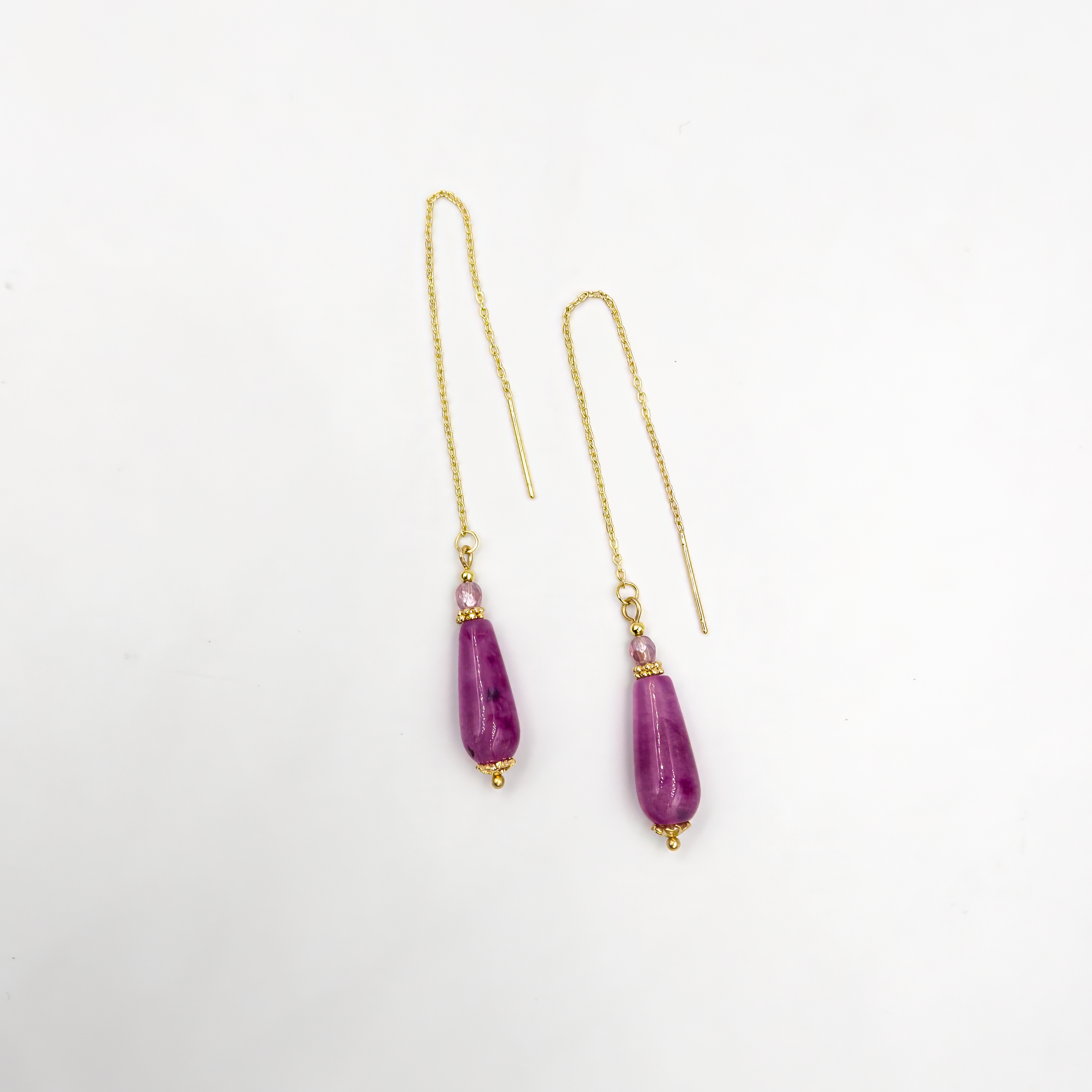 עגילים תלויים עם שרשרת דקה ואגת סגול בגוון לילך עמוק. האבן משובצת בקצה השרשרת ומוסיפה תנועה רכה וברק סגול ייחודי. תכשיט שמעניק תחושת עומק פנימי וסטייל נשי. מתאים לכל מי שאוהבת תכשיטים מיוחדים אך לבישים ביום-יום.

