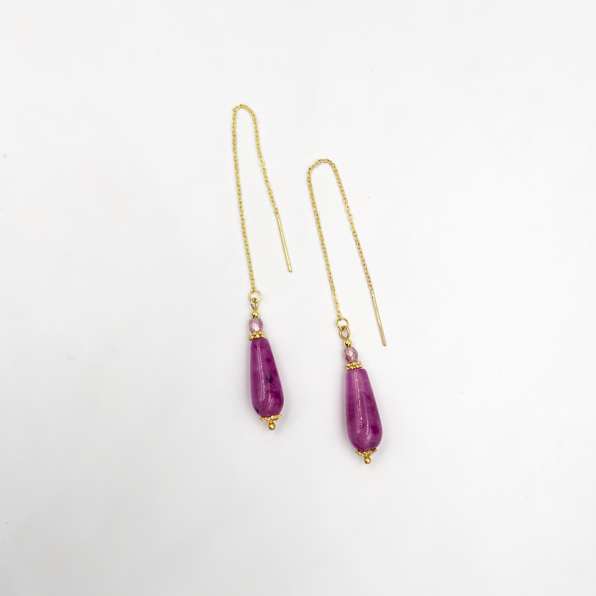 עגילים תלויים עם שרשרת דקה ואגת סגול בגוון לילך עמוק. האבן משובצת בקצה השרשרת ומוסיפה תנועה רכה וברק סגול ייחודי. תכשיט שמעניק תחושת עומק פנימי וסטייל נשי. מתאים לכל מי שאוהבת תכשיטים מיוחדים אך לבישים ביום-יום.

