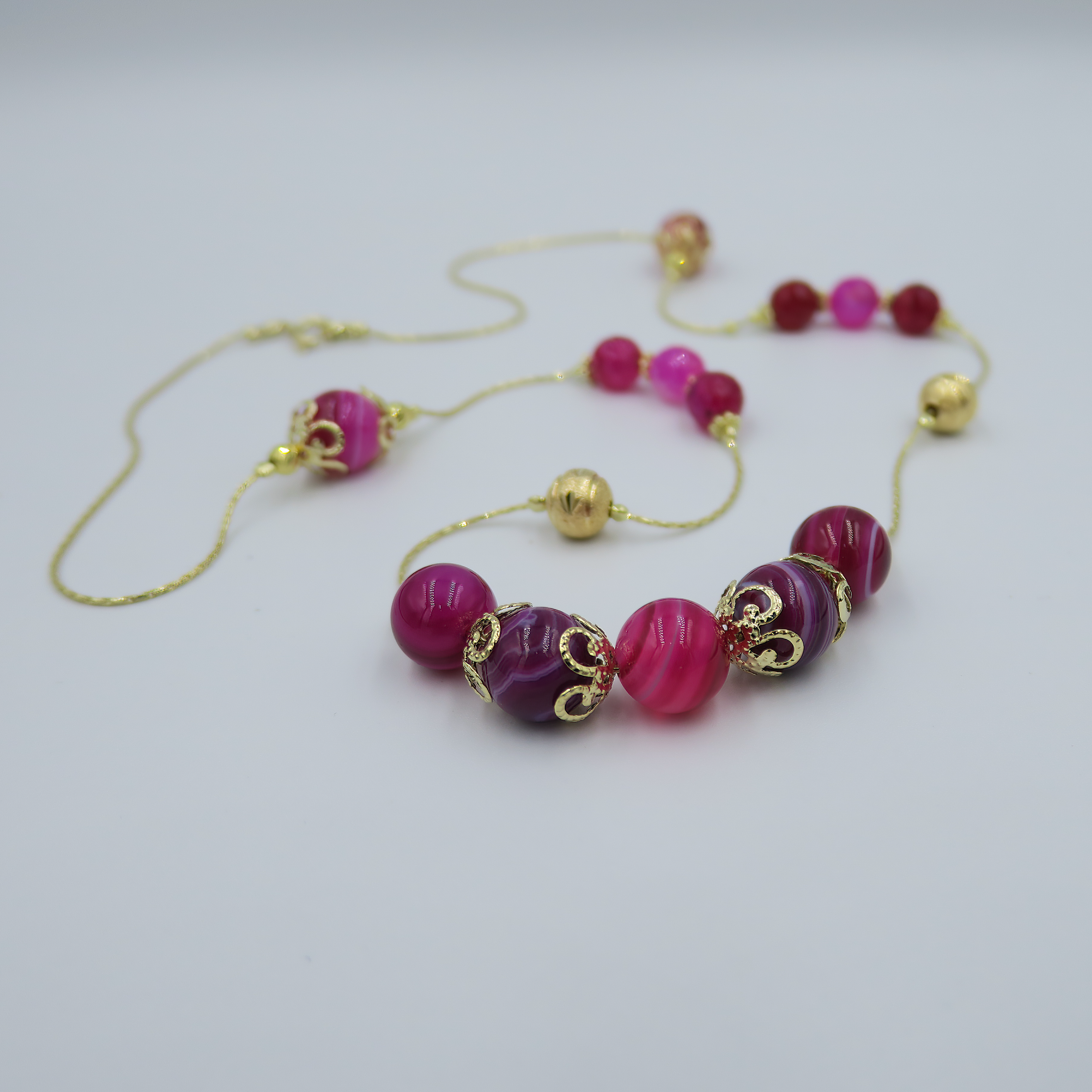 שרשרת ארוכה עשויה אבני אגט בגוונים מגוונים של סגול וורוד – תכשיט צבעוני עם אופי רגוע ונשי. השרשרת מציגה מעבר עדין בין גוונים עמוקים של סגול לשכבות ורודות רכות, הרמוניה ויזואלית שנשארת רכה ומעודנת. האורך הארוך שלה מאפשר לשלב אותה כשכבה בודדת או לעטוף פעמיים למראה מלא, עשיר ומעוצב. האגט, אבן הידועה בתכונותיה המאזנות, מוסיפה מגע אנרגטי רך לתכשיט. מתאימה לנשים שאוהבות תכשיטים עם נוכחות, צבע ומשמעות.