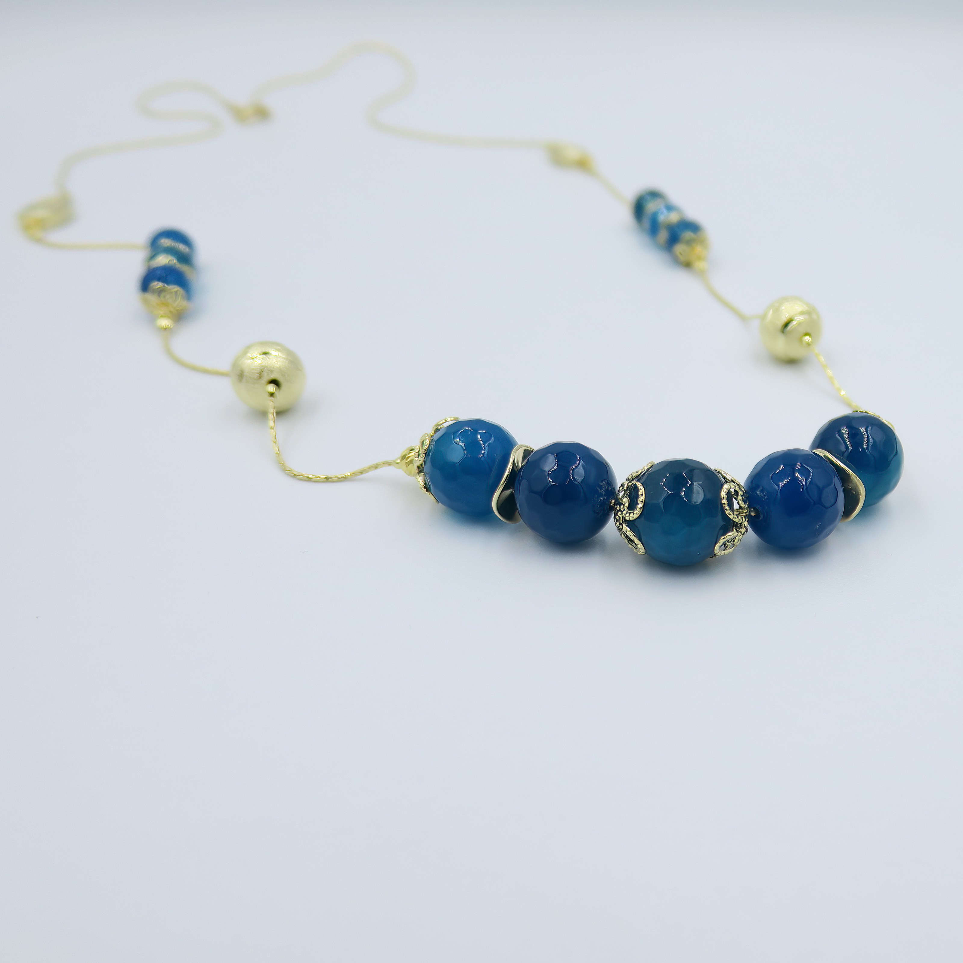 שרשרת ארוכה בעבודת יד מאבני אגט כחולות – מראה כחול עשיר שמקרין יציבות פנימית. החרוזים משתנים בין תכלת בהיר לכחול עמוק, מה שיוצר מראה שמתאים לכל עונה וסגנון. העיצוב הארוך מאפשר גמישות – ניתן לענוד את השרשרת באורך מלא או לעטוף פעמיים למראה רב-שכבתי. אבן האגט נחשבת לאבן הגנה והרגעה, ומוסיפה תמיכה רגשית דרך עיצוב טבעי. תכשיט מושלם למי שמחפשת גם צבע, גם סגנון וגם תחושת חיבור רגשי לטבע.