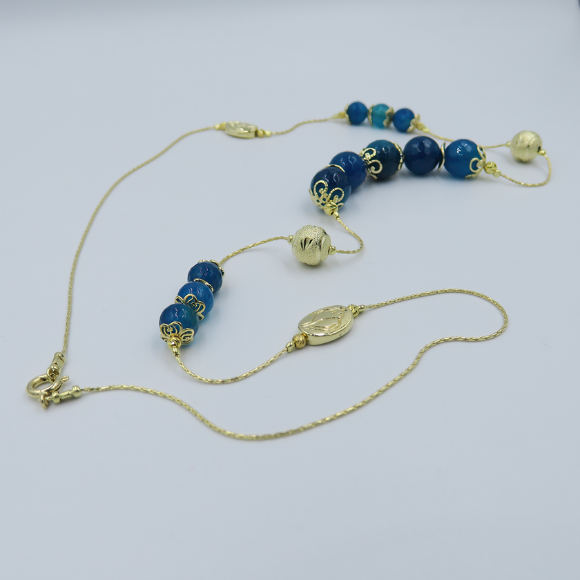 שרשרת ארוכה בעבודת יד מאבני אגט כחולות – מראה כחול עשיר שמקרין יציבות פנימית. החרוזים משתנים בין תכלת בהיר לכחול עמוק, מה שיוצר רכות צבעונית שמרגיעה את המבט. העיצוב הארוך מאפשר גמישות – ניתן לענוד את השרשרת באורך מלא או לעטוף פעמיים למראה רב-שכבתי. אבן האגט נחשבת לאבן הגנה והרגעה, ומוסיפה תמיכה רגשית דרך עיצוב טבעי. תכשיט מושלם למי שמחפשת גם צבע, גם סגנון וגם תחושת חיבור רגשי לטבע.