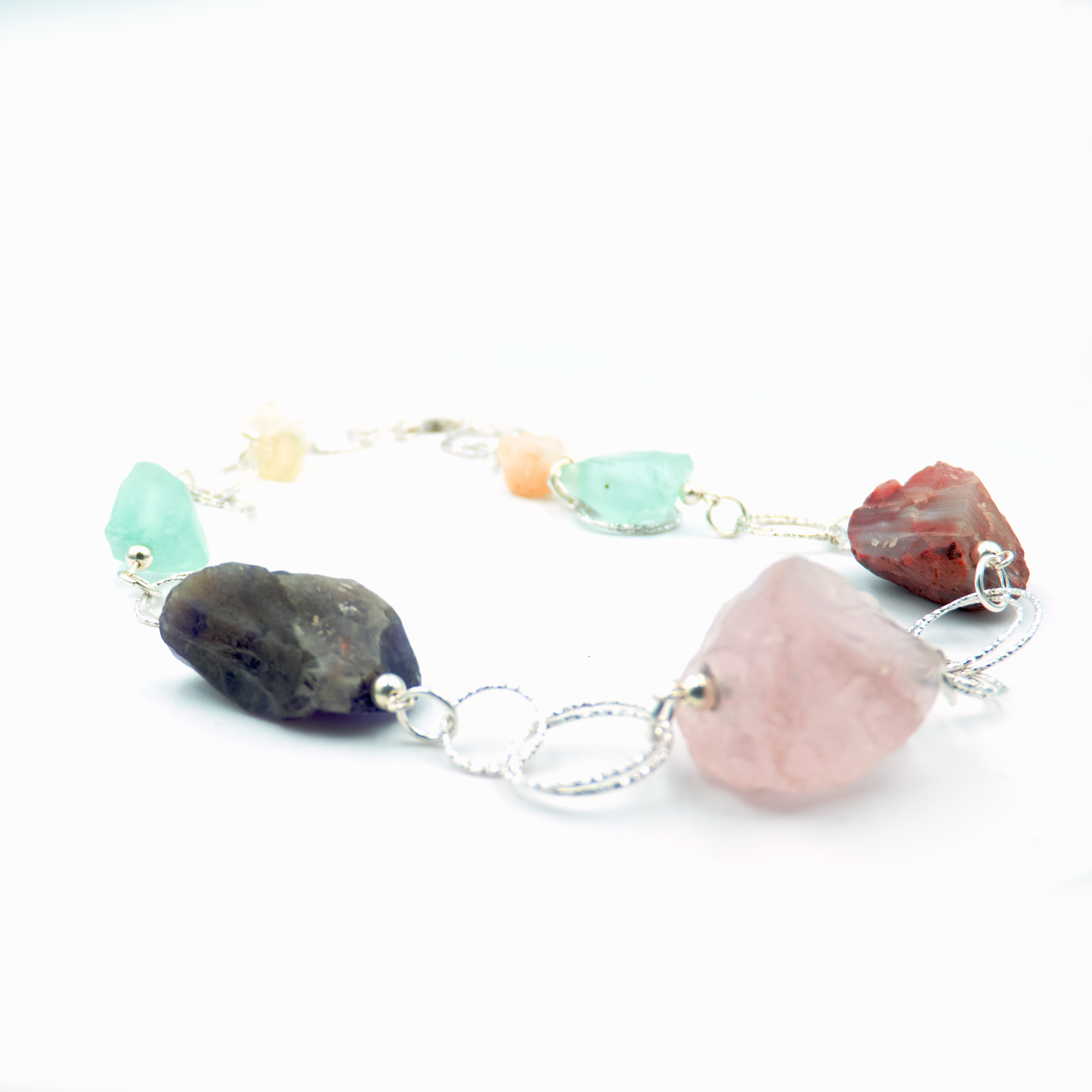 שרשרת כסף בעבודת יד שמשלבת מגוון עשיר של קריסטלים טבעיים – אמטיסט בגוון סגול עמוק, רוז קוורץ ורדרד ורך, פלואוריט בגוני ירוק וסגול שקופים, וקרנליאן חם בצבע כתום־אדמדם. ההמפגש בין האבנים יוצר איזון אנרגטי עם עומק רגשי ואנרגטי, וכל אבן מוסיפה שכבה משלה של משמעות ונוכחות. השרשרת עוצבה כך שכל אבן תוכל לנשום, ומשלב ביניהן תוך כדי משחק של צבעים, טקסטורות ושקיפויות. השרשרת לנשמות יצירתיות שמתחברות ליופי הרוחני של הטבע, כאלה שמתחברות לעוצמה שקטה ולסטייל ייחודי – וגם לאלו שמחפשות איזון, השראה ורוך. שרשרת שהיא כמו נשי