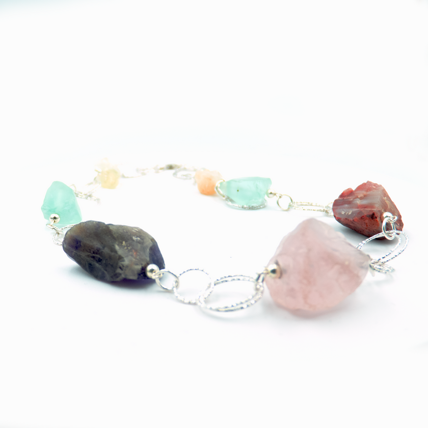 שרשרת כסף בעבודת יד שמשלבת מגוון עשיר של קריסטלים טבעיים – אמטיסט בגוון סגול עמוק, רוז קוורץ ורדרד ורך, פלואוריט בגוני ירוק וסגול שקופים, וקרנליאן חם בצבע כתום־אדמדם. ההמפגש בין האבנים יוצר איזון אנרגטי עם עומק רגשי ואנרגטי, וכל אבן מוסיפה שכבה משלה של משמעות ונוכחות. השרשרת עוצבה כך שכל אבן תוכל לנשום, ומשלב ביניהן תוך כדי משחק של צבעים, טקסטורות ושקיפויות. השרשרת לנשמות יצירתיות שמתחברות ליופי הרוחני של הטבע, כאלה שמתחברות לעוצמה שקטה ולסטייל ייחודי – וגם לאלו שמחפשות איזון, השראה ורוך. שרשרת שהיא כמו נשי