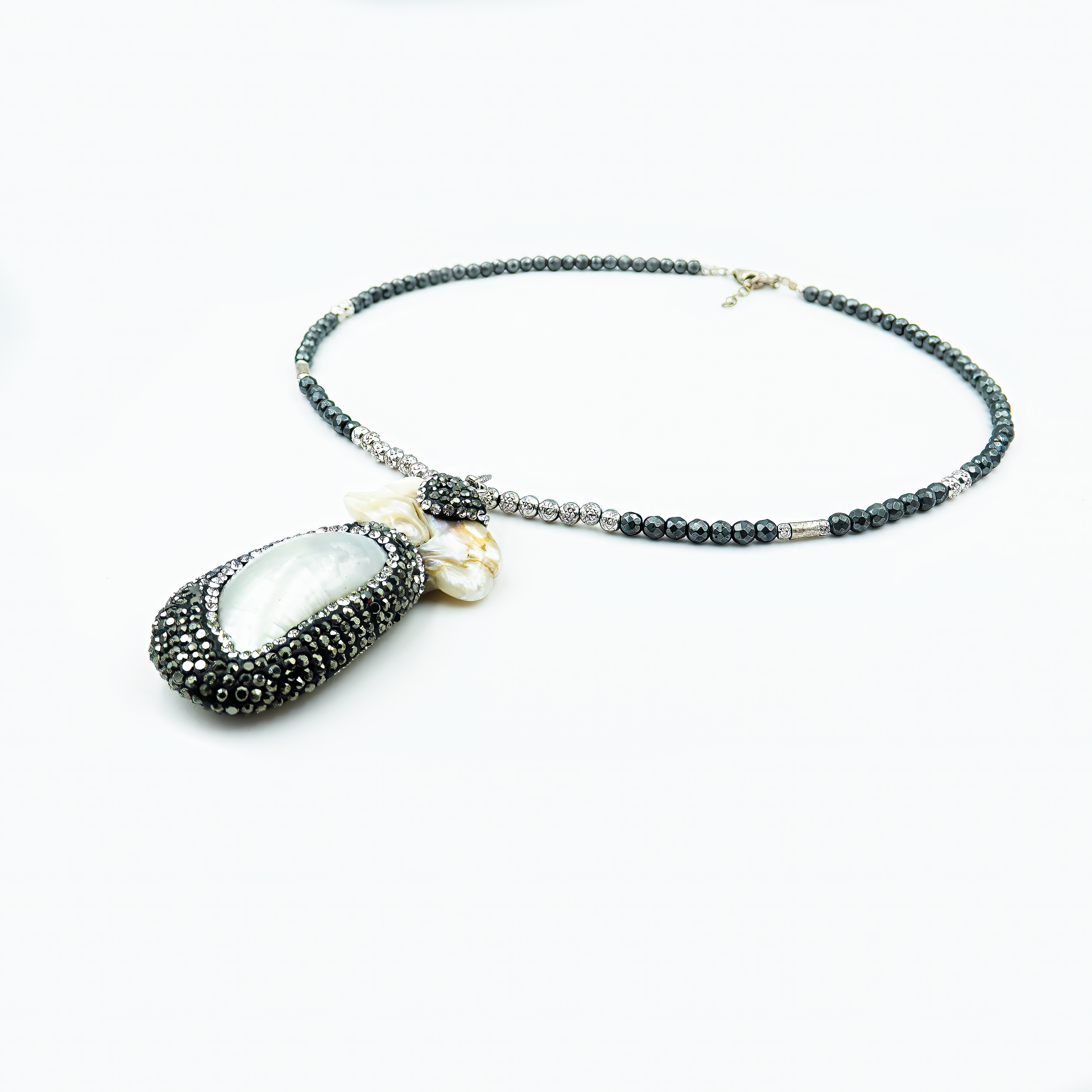 תכשיט שמשלב עוצמה ועדינות – תליון פנינה גדול עם נצנוץ ייחודי מוקף קריסטלים כהים, תלוי משרשרת חרוזים שחורים מבריקים. מתאים לערב או אירוע מיוחד, עם שמלה שחורה או חולצה לבנה קלאסית. נוכחות שאי אפשר להתעלם ממנה.