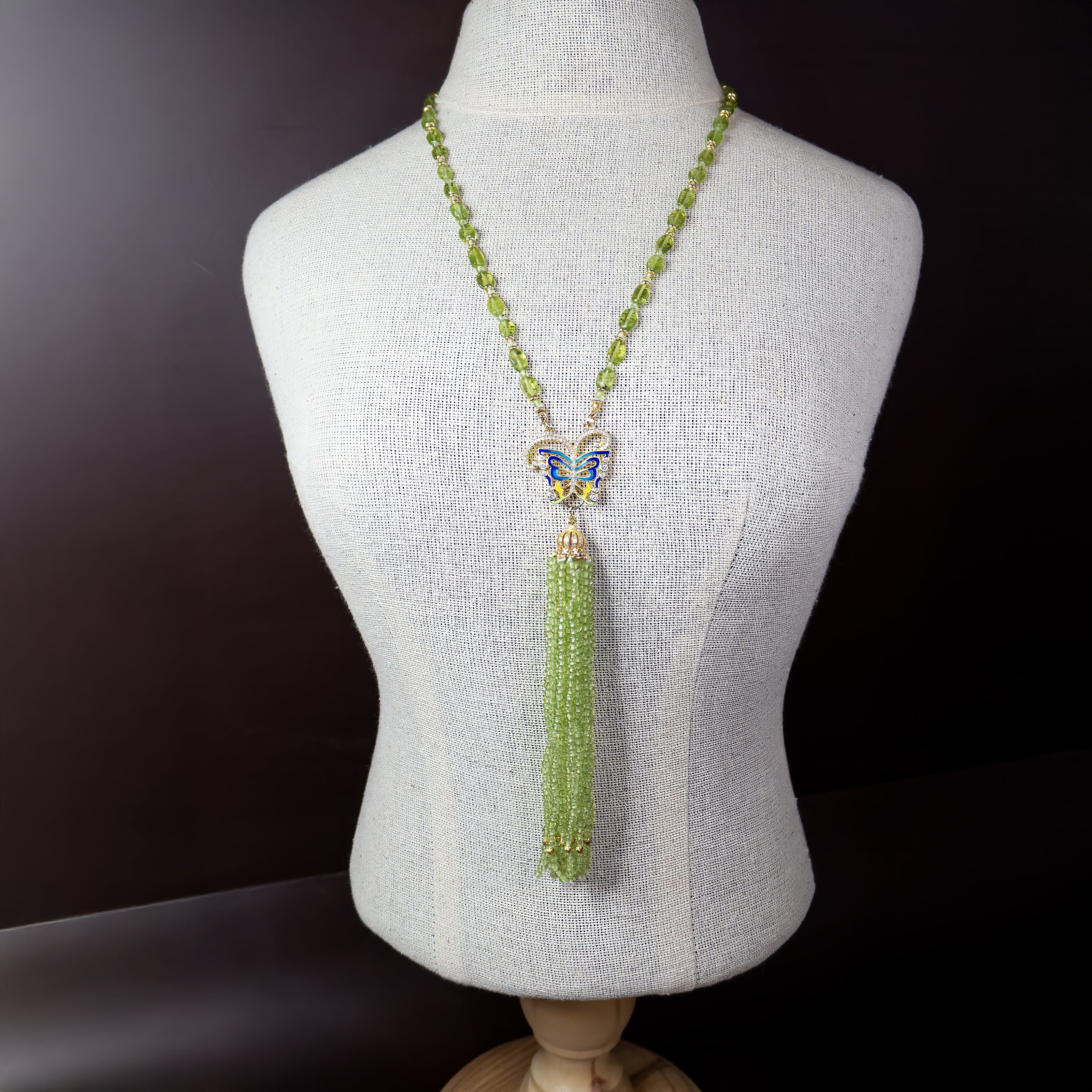 תכשיט שמרגיש כמו סיפור אגדה – שרשרת מרהיבה המשלבת אבני פרידוט בגוון ירוק מרענן עם תליון פרפר צבעוני באמייל כחול ולבן. מהפרפר משתלשלים גדילים רבים של חרוזים ירוקים שמזכירים מפל נוזל של אור וטבע. התנועה הרכה של הגדילים יחד עם הנצנוץ העדין יוצרים תחושת קלילות, חופש ונשיות. מושלמת להופעה עם שמלה קלילה, חולצה לבנה או כל לוק שמבקש טאץ’ של רומנטיקה ושיק טבעי. תכשיט שמדבר ללב ומחבר אותך לטבע.