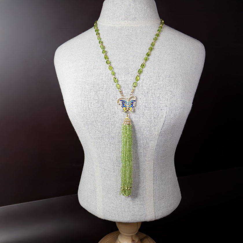 תכשיט שמרגיש כמו סיפור אגדה – שרשרת מרהיבה המשלבת אבני פרידוט בגוון ירוק מרענן עם תליון פרפר צבעוני באמייל כחול ולבן. מהפרפר משתלשלים גדילים רבים של חרוזים ירוקים שמזכירים מפל נוזל של אור וטבע. התנועה הרכה של הגדילים יחד עם הנצנוץ העדין יוצרים תחושת קלילות, חופש ונשיות. מושלמת להופעה עם שמלה קלילה, חולצה לבנה או כל לוק שמבקש טאץ’ של רומנטיקה ושיק טבעי. תכשיט שמדבר ללב ומחבר אותך לטבע.