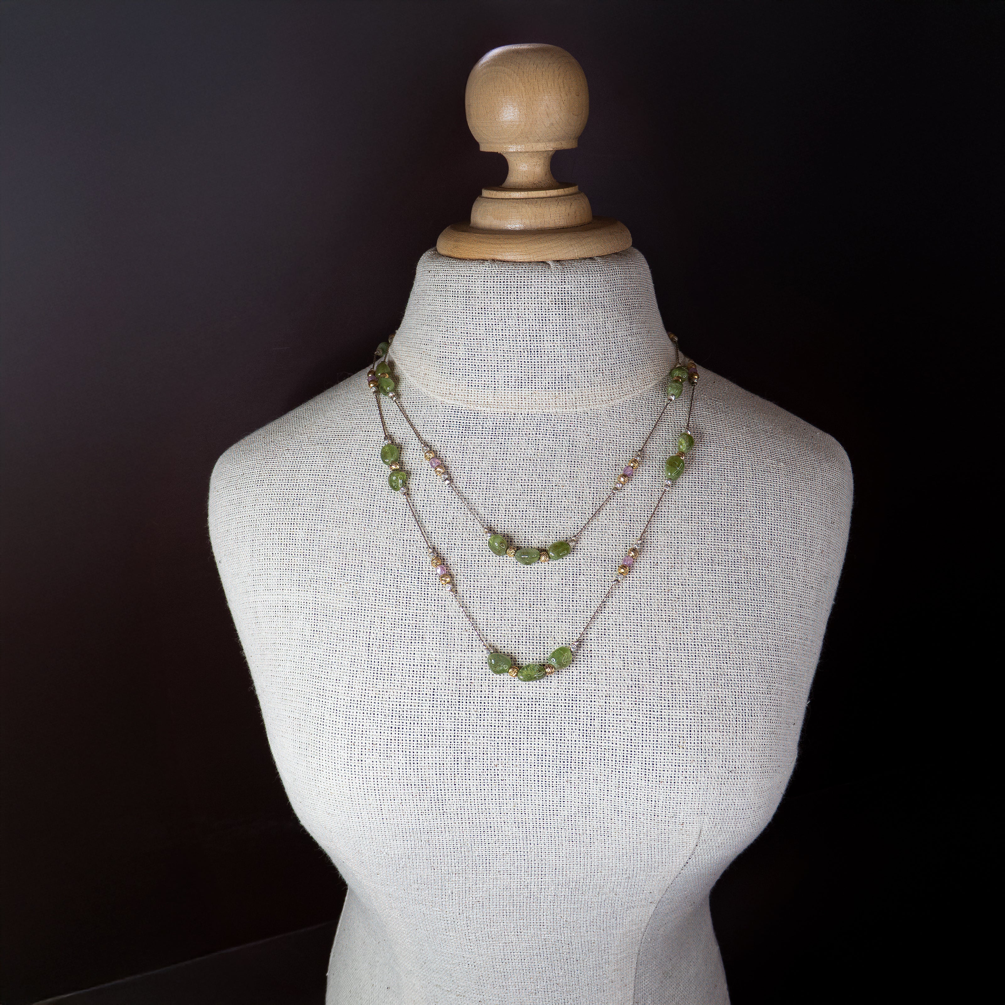 שרשרת ייחודית בעבודת יד עם אבני חן ירוקות בגימור חלק ולא סימטרי, חרוזים מתכתיים מוזהבים וכסופים, ואלמנטים בגוון ורוד פנינה. השרשרת משדרת תחכום ועדינות, מושלמת ליום או ערב. מוצגת על רקע אחיד ורוד-פודרה, אשר מדגיש את גווני השרשרת ואת הברק העדין שלה.
המחיר מתייחס לשרשרת אחד בלבד