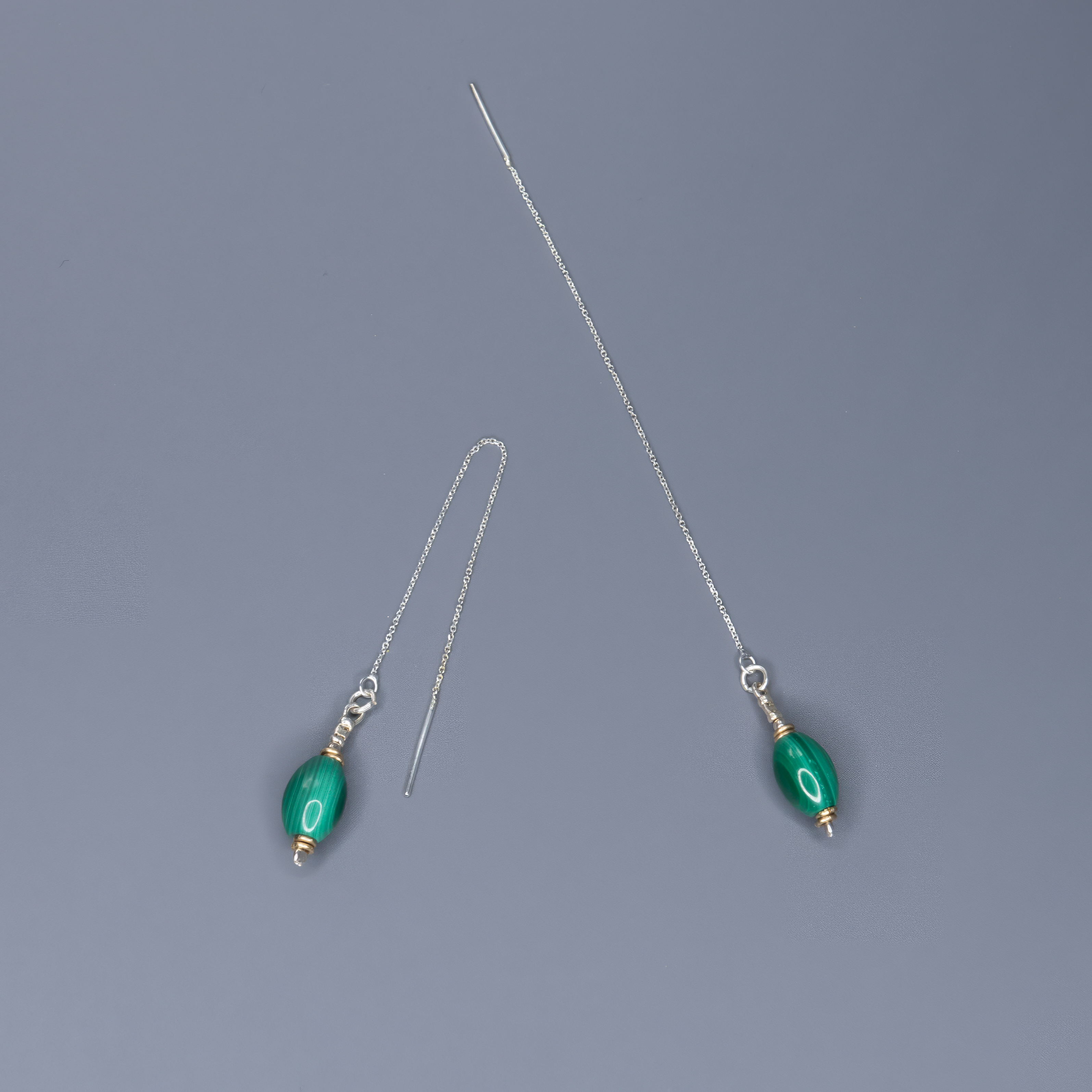 עגילי שרשרת בעבודת יד עם אבן מלכית טבעית בגוון ירוק עמוק ופסים טבעיים מרהיבים. העיצוב משלב שרשרת דקה ומתכת איכותית עם אבן בעלת נוכחות יוצאת דופן. המלכית ידועה כאבן שמסמלת הגנה, טרנספורמציה ואיזון רגשי. כל אבן שונה ומיוחדת בפני עצמה, מה שהופך כל זוג עגילים ליחיד במינו. התכשיט משדר אלגנטיות שקטה, חיבור לטבע ותחכום מודרני. מתאים לנשים שמחפשות תכשיט יוקרתי ולא שגרתי – קליל אך מלא סטייל.

