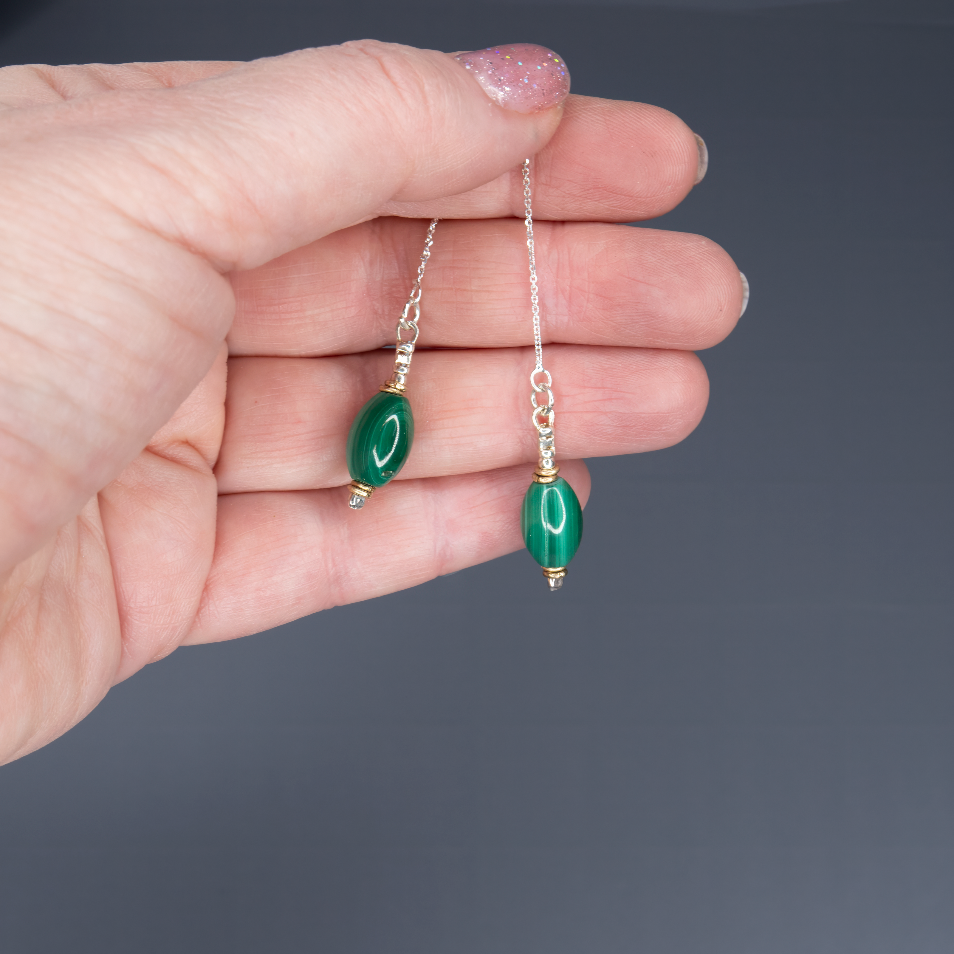 עגילים ארוכים עם שרשרת מתכת דקיקה ואבן מלכית טבעית בגוון ירוק עמוק ומלא חיים. המלכית נחשבת לאבן עוצמתית המחזקת רוגע, אינטואיציה ויציבות פנימית. כל אבן מלוטשת ביד ומשובצת בקפידה ליצירת מראה הרמוני ומאוזן. העגילים קלילים אך מלאי נוכחות, מתאימים ללבוש יומיומי אלגנטי או להופעות ערב יוקרתיות. מתנה נהדרת לאישה שמעריכה תכשיטים עם משמעות, עיצוב מוקפד וחיבור לטבע.

