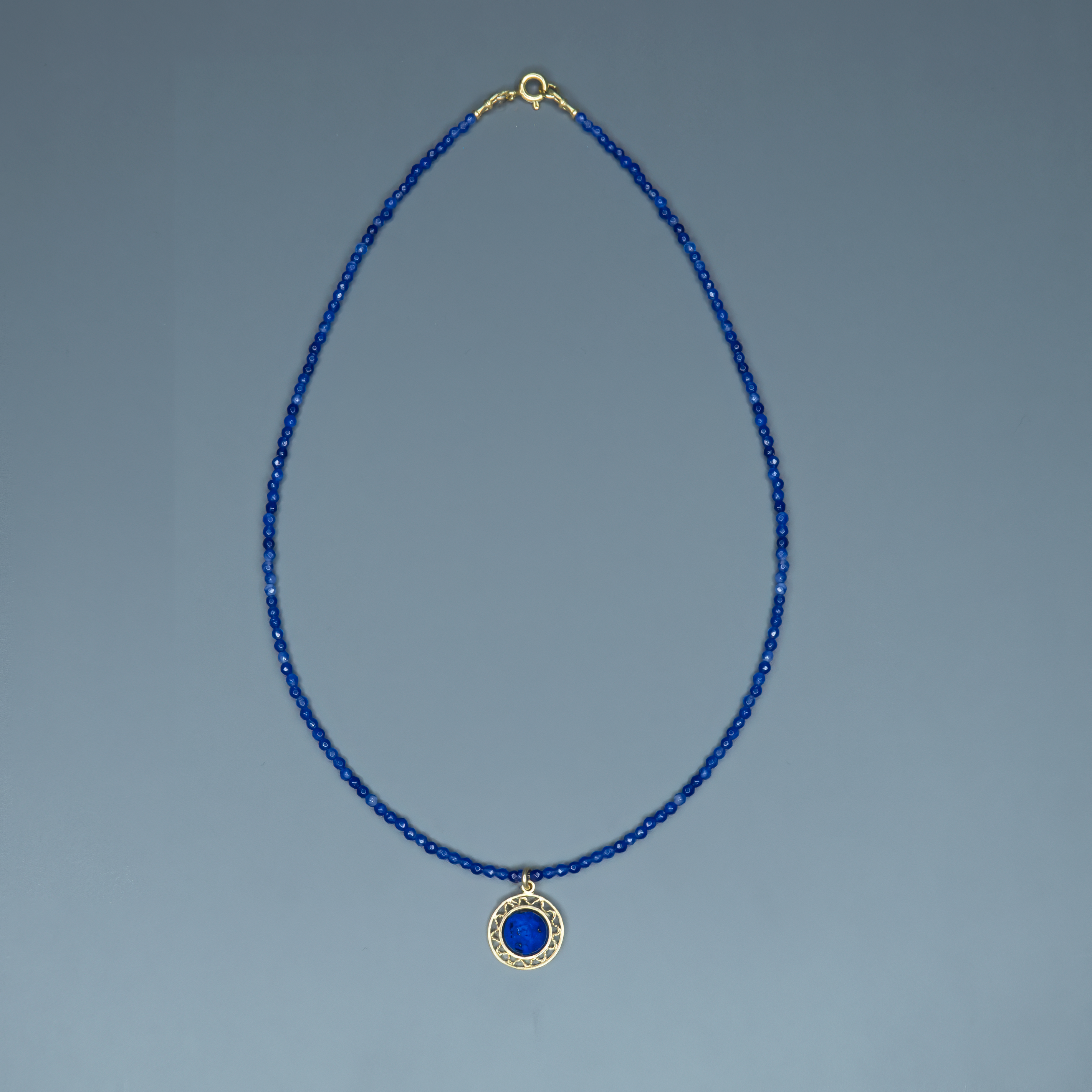 שרשרת קולר בגוון כחול עמוק עם תליון מוזהב עגול, שבתוכו משובצת אבן כחולה מבריקה, יוצרת מראה יוקרתי אך מודרני. החרוזים הקטנים מעניקים תחושת דיוק ועדינות, בעוד שהתליון מוסיף נוכחות מרשימה. מונחת על צוואר נקי שמדגיש את עיצוב השרשרת, והצילום מדגיש את קווי המתאר הנשיים. תכשיט מושלם לערב אלגנטי, אירוע עסקי או מתנה מתחשבת עם הרבה סטייל.