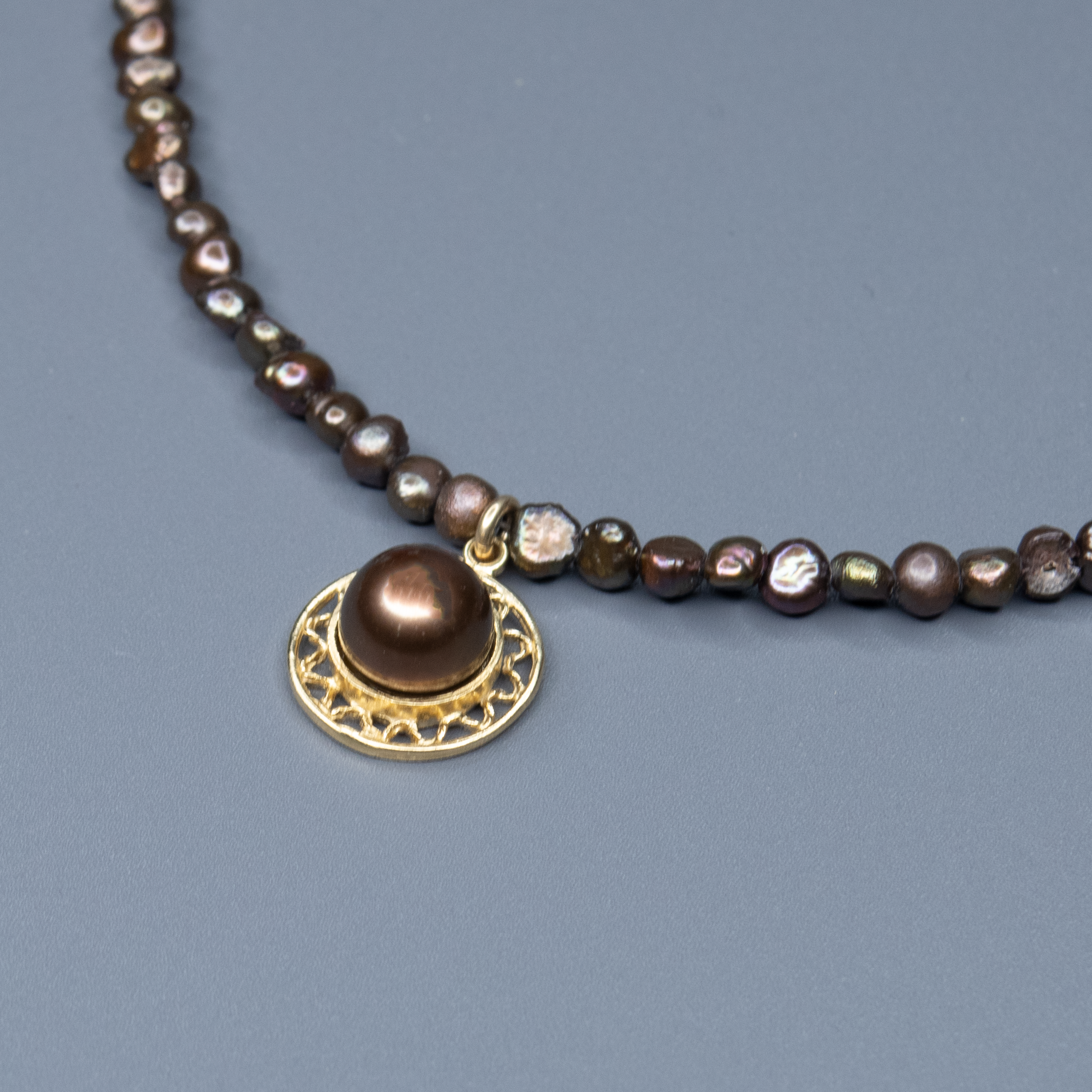 שרשרת פנינים בגווני שוקולד עשירים עם תליון מרכזי – פריט ייחודי עם ניחוח של יוקרה שקטה. הפנינים בצבעי חום, ברונזה וקוניאק יוצרים שילוב של צבעים חמים עם נגיעה קלאסית. התליון מוסיף פרט מרכזי שמדגיש את הקו האישי, שמושך את העין ומשלים את המראה הכללי. השילוב בין גווני האדמה לבין הברק הפנינתי מעניק לשרשרת תחושת עושר שקט וסטייל מודרני, שמתאימים גם ליום וגם לערב. שרשרת שמתחברת לנשיות חזקה, לאהבה לפרטים ולנוכחות שקטה שמתאימה לכל אישיות.