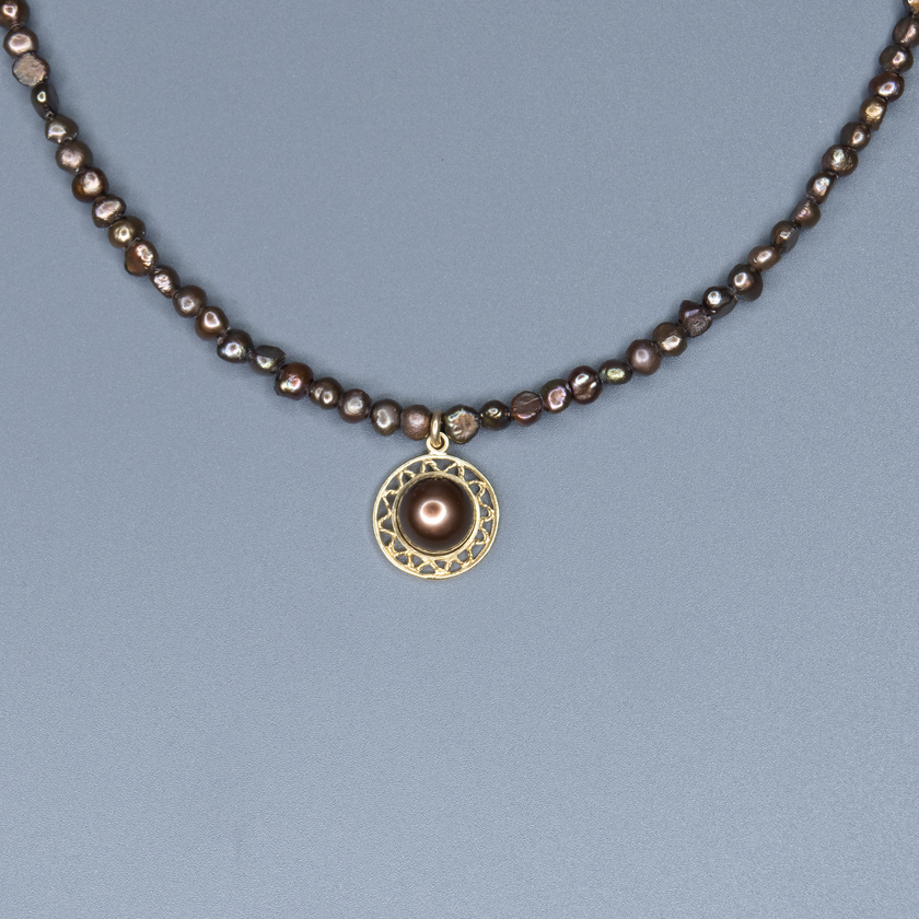 שרשרת פנינים בגווני שוקולד עשירים עם תליון מרכזי – תכשיט עם חום פנימי ואלגנטיות טבעית. הפנינים בצבעי חום, ברונזה וקוניאק יוצרים מראה עשיר בגוונים טבעיים שמתאים לכל עונה. התליון מוסיף טוויסט עדין שהופך את השרשרת לבלתי שגרתית, שמושך את העין ומשלים את המראה הכללי. השילוב בין גווני האדמה לבין הברק הפנינתי מעניק לשרשרת תחושת עושר שקט וסטייל מודרני, שמתאימים גם ליום וגם לערב. שרשרת שמתחברת לנשיות חזקה, לאהבה לפרטים ולנוכחות שקטה שמתאימה לכל אישיות.