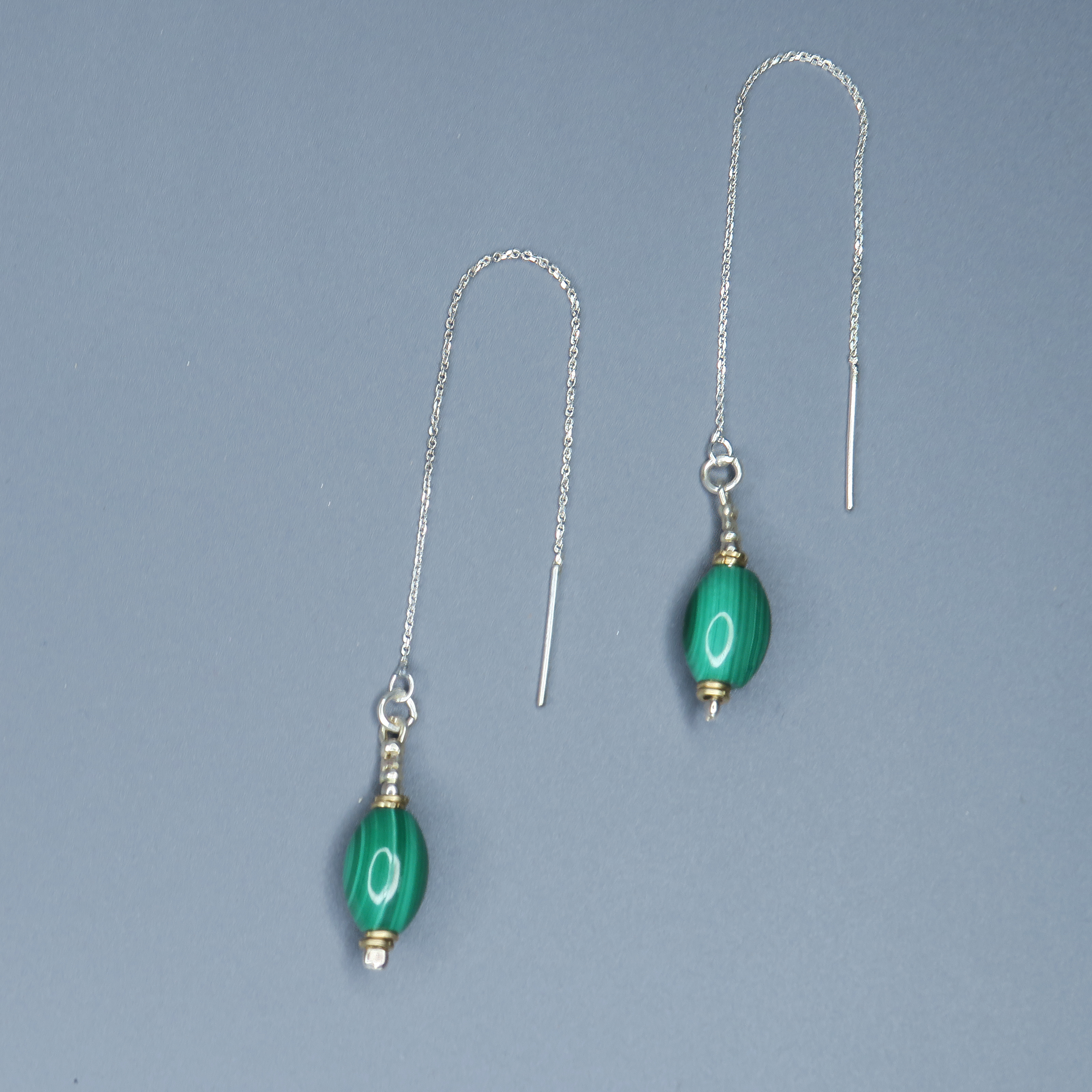 עגילים תלויים בעיצוב אלגנטי עם שרשרת כסף או זהב עדינה ואבן מלכית בגוון ירוק־אזמרגד עמוק. האבן בעלת טקסטורה טבעית משתנה שמוסיפה אופי ועומק לכל עגיל. העיצוב היוקרתי מתאים למראה ערב חגיגי או ללוק קלאסי עם נגיעה מיוחדת. המלכית מסמלת שקט פנימי ועוצמה רגועה, והעגילים עצמם משדרים יוקרה עם נוכחות מתוחכמת. תכשיט אידיאלי למתנה לאישה עם טעם מדויק וחיבור ליופי טבעי.

