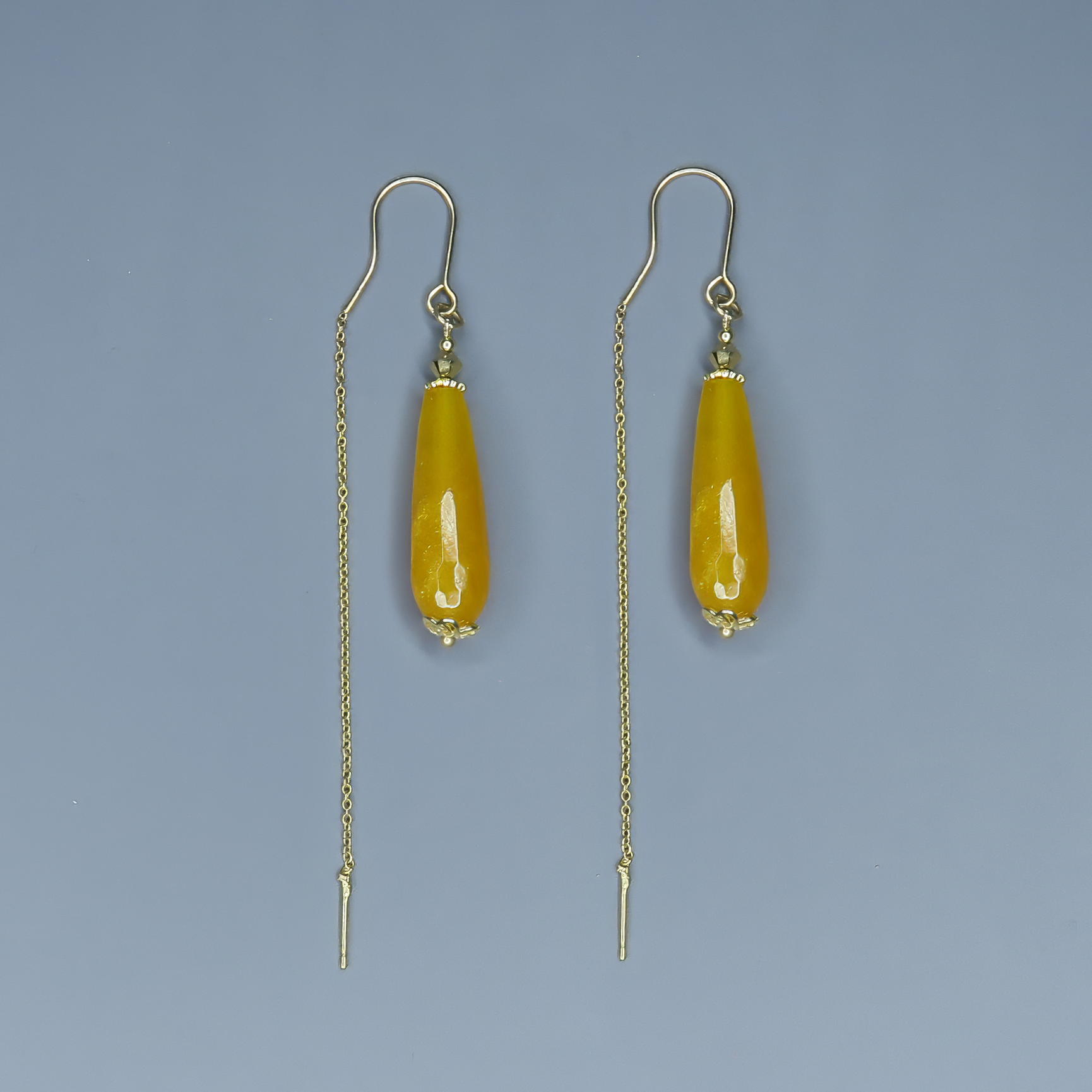 עגילי שרשרת בעבודת יד עם אבן אגת טבעית בגוון צהוב שמש – צבע חמים, מואר ומלא חיים. האבן משתלשלת בקצה שרשרת עדינה ויוצרת תנועה רכה וזורמת. עיצוב שמקרין שמחה, קלילות ואלגנטיות טבעית. מתאים לנשים שאוהבות צבע עם נוכחות שקטה וסטייל אישי.

