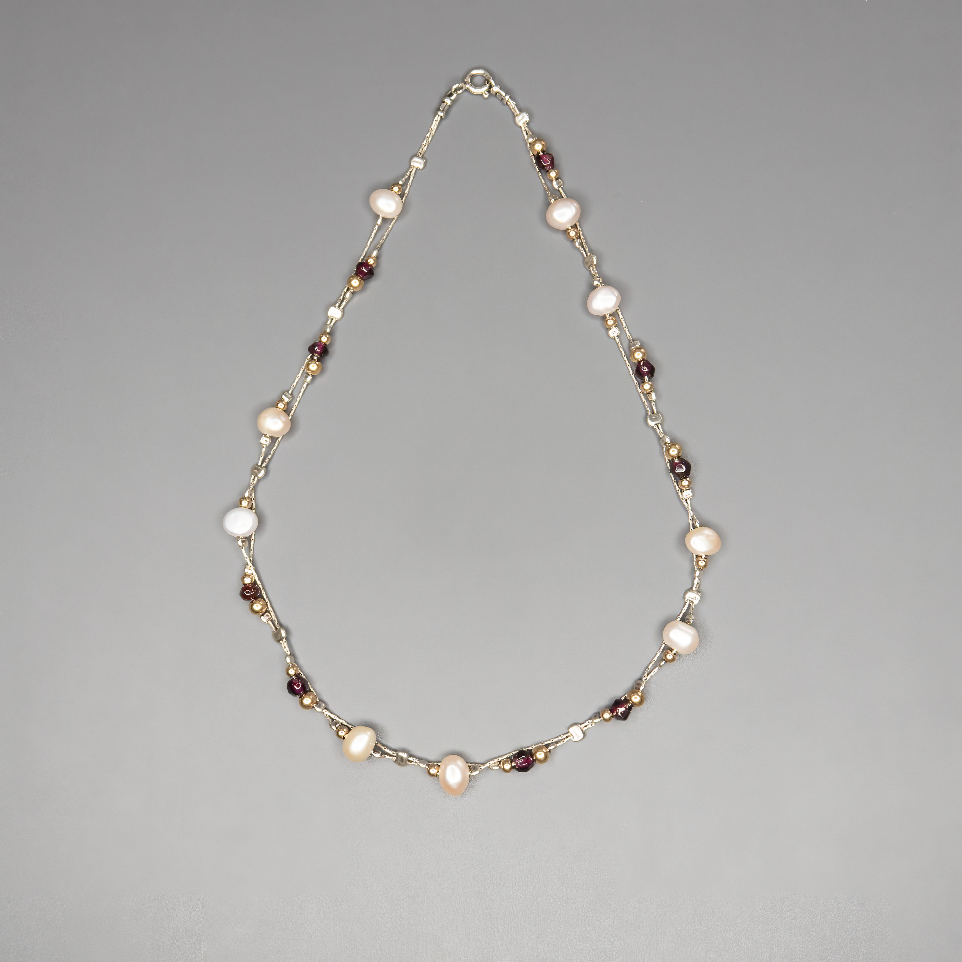 שרשרת כסף בעבודת יד המשלבת פנינים לבנות טבעיות עם גרנטים עמוקים בגוון יין – שילוב ייחודי בין רוך הפנינה לעומק הדרמטי של הגרנט. הפנינים מוסיפות אור ורכות לכל הופעה, בעוד שהגרנטים מביאים עומק, חמימות ונשיות עם נוכחות שקטה ומרגשת. השרשרת עשויה מכסף סטרלינג 925, עם סגירה מעודנת שמשלימה את הקו האלגנטי של התכשיט. תכשיט שמתאים לאירועים מיוחדים אך גם לבעלות סגנון אישי שמבקשות לשלב מראה על־זמני עם קריצה עדכנית.