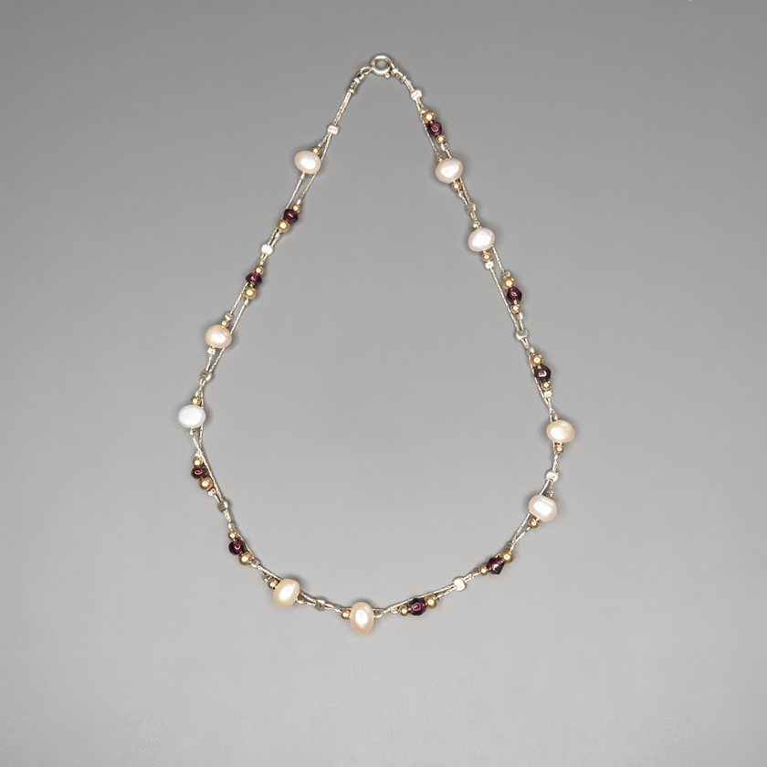 שרשרת כסף בעבודת יד המשלבת פנינים לבנות טבעיות עם גרנטים עמוקים בגוון יין – שילוב ייחודי בין רוך הפנינה לעומק הדרמטי של הגרנט. הפנינים מוסיפות אור ורכות לכל הופעה, בעוד שהגרנטים מביאים עומק, חמימות ונשיות עם נוכחות שקטה ומרגשת. השרשרת עשויה מכסף סטרלינג 925, עם סגירה מעודנת שמשלימה את הקו האלגנטי של התכשיט. תכשיט שמתאים לאירועים מיוחדים אך גם לבעלות סגנון אישי שמבקשות לשלב מראה על־זמני עם קריצה עדכנית.