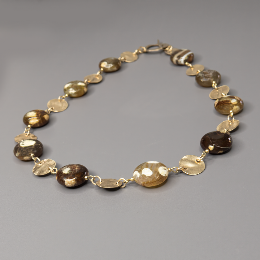 שרשרת אבן פיקאסו בעיבוד ייחודי בעבודת יד, עם מתכת גולדפילד זהובה ונגיעות של עיצוב בוהו־שיק טבעי. האבנים בתערובת של בז', אפור וחמרה, יוצרות מראה הרמוני, עשיר ומעורר סקרנות – כל אבן נראית כמו ציור מינרלי ייחודי. השרשרת משלבת בין צבעים חמים, מרקמים חיים וזוהר עדין של זהב, ומעניקה תחושת עומק, קרקע ונשימה איטית. מתאימה לנשים עם סגנון אישי מובהק, שמחפשות תכשיט ייחודי, מעודן אך נוכח, שמשדר סגנון בוטני־אורבני. פריט מושלם ליום־יום עם טאץ' אחר, או כתוספת שקטה אך אלגנטית למראה ערב פשוט ונעים.