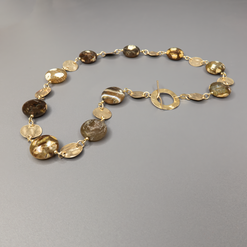 שרשרת אבן פיקאסו בעיבוד ייחודי בעבודת יד, עם מתכת גולדפילד זהובה ונגיעות של עיצוב בוהו־שיק טבעי. האבנים בגווני טבע חמים, יוצרות מראה הרמוני, עשיר ומעורר סקרנות – כל אבן נראית כמו ציור מינרלי ייחודי. השרשרת משלבת בין צבעים חמים, פני שטח משתנים וזוהר עדין של זהב, ומעניקה תחושת עומק, קרקע ונשימה איטית. מתאימה לנשים עם סגנון אישי מובהק, שמחפשות תכשיט ייחודי, מעודן אך נוכח, שמשדר תחושת עומק עם ייחוד אישי. פריט מושלם ליום־יום עם טאץ' אחר, או כתוספת שקטה אך אלגנטית למראה ערב פשוט ונעים.