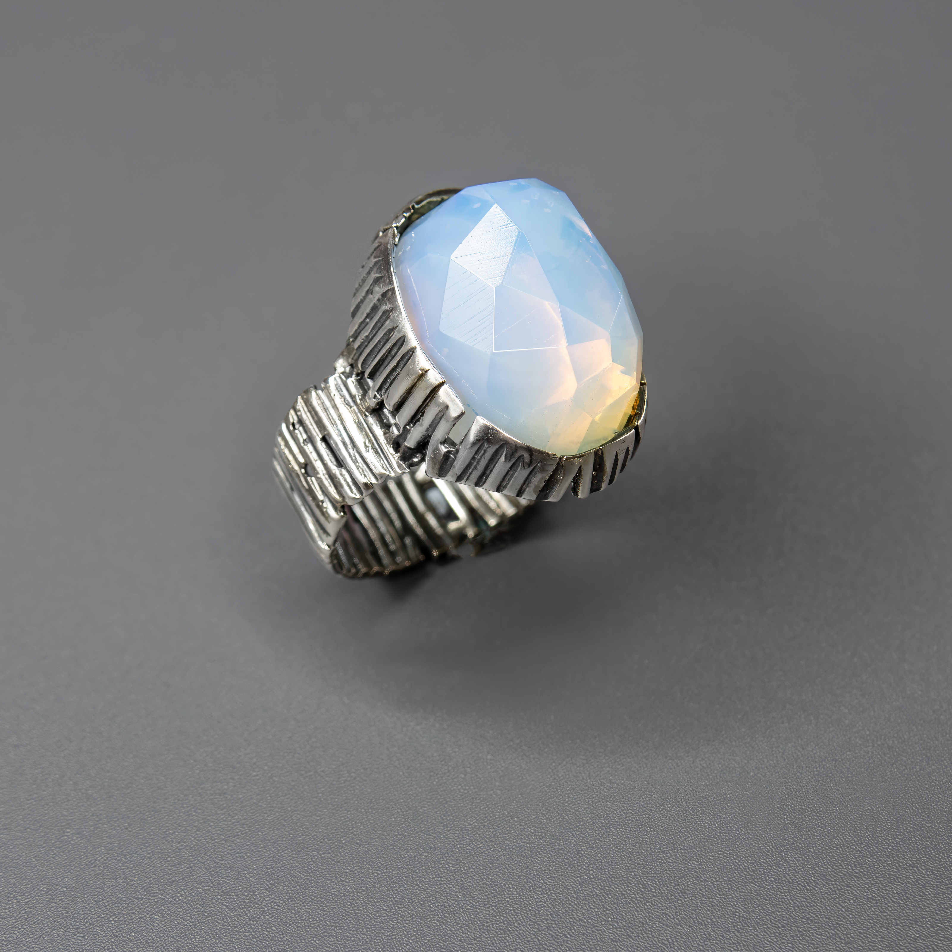 תכשיט כסף בעבודת יד המעוטר באבן אופליט לבנה בצורת אובלית, בעלת לבן־פנינה שמעניק תחושת ניקיון, רוגע והרמוניה. האבן הלבנה מלוטשת למראה חלק ונעים למגע, ומשדרת זוהר שקט המשתנה בהתאם לזווית התאורה – לפעמים נראית כמעט שקופה, לפעמים עם ברק פנינתי עדין. היא מהווה נקודת אור מרכזית בתכשיט, ומתאימה לאוהבי עיצוב אלגנטי, מינימליסטי ובעל השראה שקטה. האבן מסמלת רוגע פנימי ותחושת השראה – מושלמת כתוספת ייחודית למראה יומיומי בהיר, וגם כפריט אלגנטי לערב מיוחד. מתנה מעולה לאישה שאוהבת תכשיטים שקטים עם משמעות עמוקה וזוהר שקט אמ