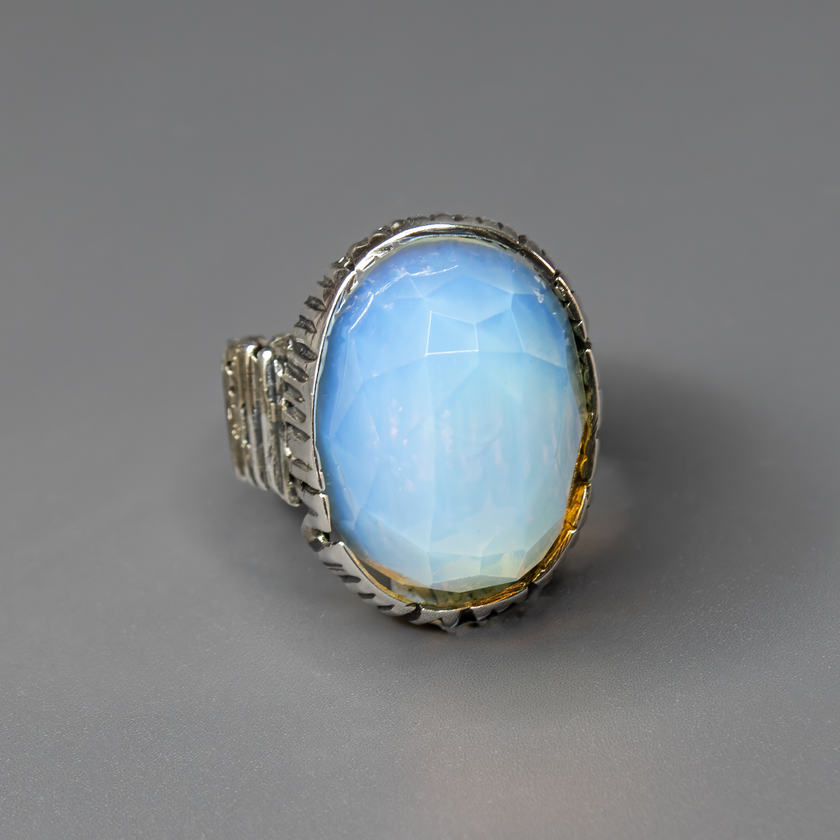 תכשיט כסף בעבודת יד המעוטר באבן אופליט לבנה בצורת אובלית, בעלת לבן־פנינה שמעניק תחושת ניקיון, רוגע והרמוניה. האבן הלבנה מלוטשת למראה חלק ונעים למגע, ומשדרת אור חלומי המשתנה בהתאם לזווית התאורה – לפעמים נראית כמעט שקופה, לפעמים עם ברק פנינתי עדין. היא מהווה נקודת אור מרכזית בתכשיט, ומתאימה לאוהבי עיצוב אלגנטי, מינימליסטי ובעל עידון רגשי. האבן מסמלת רוגע פנימי ותחושת השראה – מושלמת כתוספת ייחודית למראה יומיומי בהיר, וגם כפריט אלגנטי לערב מיוחד. מתנה מעולה לאישה שאוהבת תכשיטים שקטים עם משמעות עמוקה ואור חלומי 