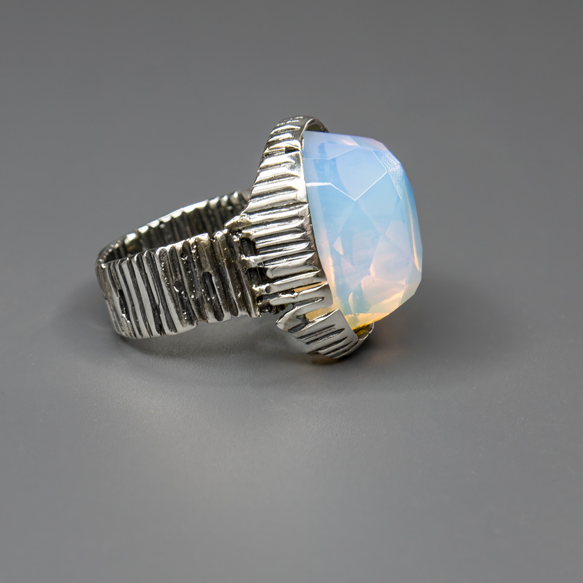 תכשיט כסף בעבודת יד המעוטר באבן אופליט לבנה בצורת אובלית, בעלת ערפילי ועדין שמעניק תחושת ניקיון, רוגע והרמוניה. האבן הלבנה מלוטשת למראה חלק ונעים למגע, ומשדרת ברק טבעי המשתנה בהתאם לזווית התאורה – לפעמים נראית כמעט שקופה, לפעמים עם ברק פנינתי עדין. היא מהווה נקודת אור מרכזית בתכשיט, ומתאימה לאוהבי עיצוב אלגנטי, מינימליסטי ובעל עידון רגשי. האבן מסמלת אנרגיה רגועה וטוהר לב – מושלמת כתוספת ייחודית למראה יומיומי בהיר, וגם כאביזר מרשים לאירועים. מתנה מעולה לאישה שאוהבת תכשיטים שקטים עם משמעות עמוקה וברק טבעי אמי