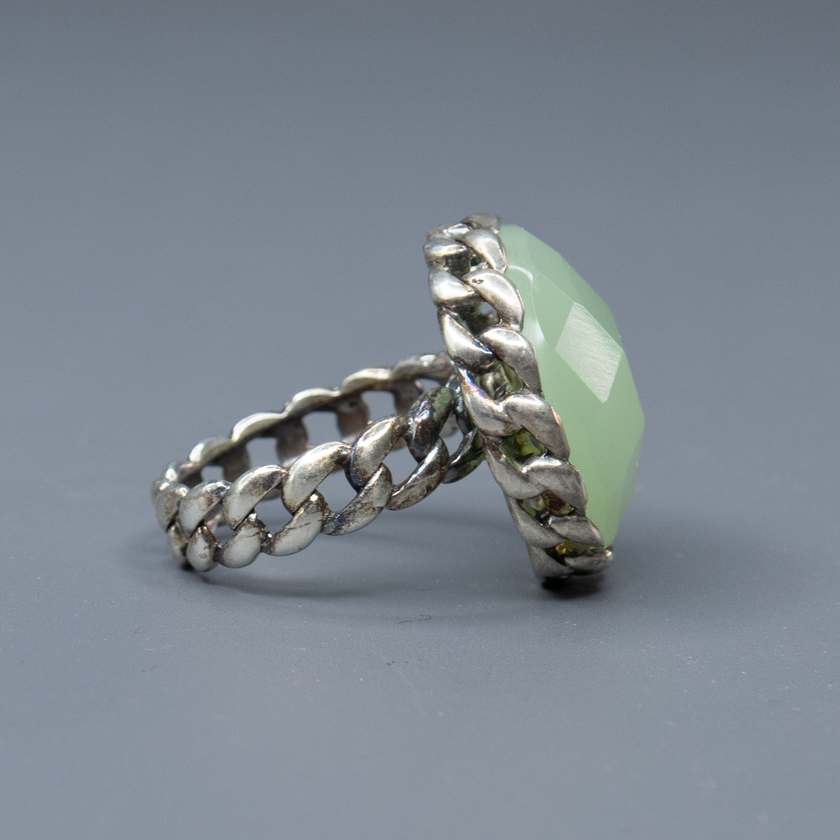 תכשיט כסף בעבודת יד המעוטר באבן אופליט ירוקה בצורת אובלית, בעלת גוון טבעי המזכיר מים ירקרקים בגוון זית. האבן מלוטשת בגימור חלק המשקף אור בצורה רכה, עם זוהר טבעי שמשתנה בהתאם לזווית התאורה. הירוק הרך משדר חיבור לאדמה ואנרגיה שלווה, ויוצר תכשיט שמשלב בין עיצוב עדין לנוכחות בולטת. האבן משתלבת בהרמוניה עם גוון הכסף ויוצרת עיצוב על־זמני ומעודכן. מתאים למי שאוהבת תכשיטים עם השראה מהטבע, סגנון נשי מרגיע ואסתטיקה אלגנטית וזורמת. מושלם כמתנה עם משמעות או פריט שמשדר עדינות וחוסן.