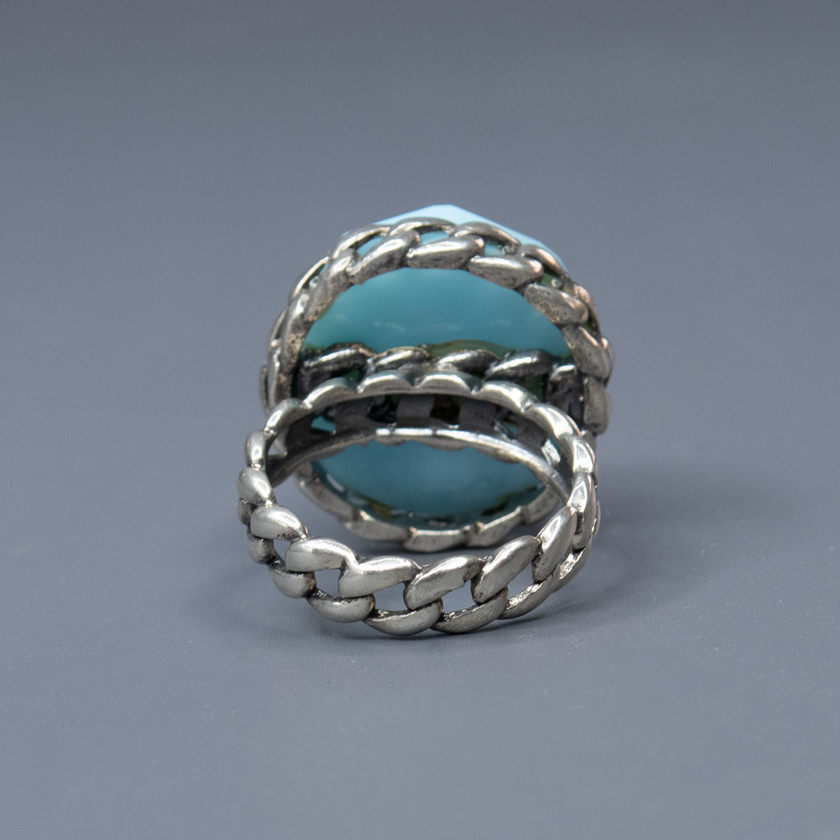 טבעת כסף בעבודת יד, כוללת באבן אופליט אובלית בגוון כחול שמימי – צבע שמזכיר שמיים רכים או אור על פני המים. האבן מלוטשת בצורה עגולה חלקה, בעלת שקיפות פנינה קלה ואפקט זוהר פנימי שמתחלף לפי התאורה. הטבעת משדרת עידון, שלווה רגישה ונוכחות שמושכת מבטים בלי להתאמץ. שילוב בין מתכת הכסף הקרה לבין הגוון התכול הרך יוצר איזון בין אסתטיקה נשית, בין אלגנטיות לאור טבעי. מתאימה לנשים שמחפשות עדות לאופי – רכה אך מדויקת, רגישה אך חזקה. מושלמת כמתנה עם משמעות, פריט יומיומי עם רוך אמנותי, או כתכשיט לאירוע חגיגי באווירה רגועה ומ