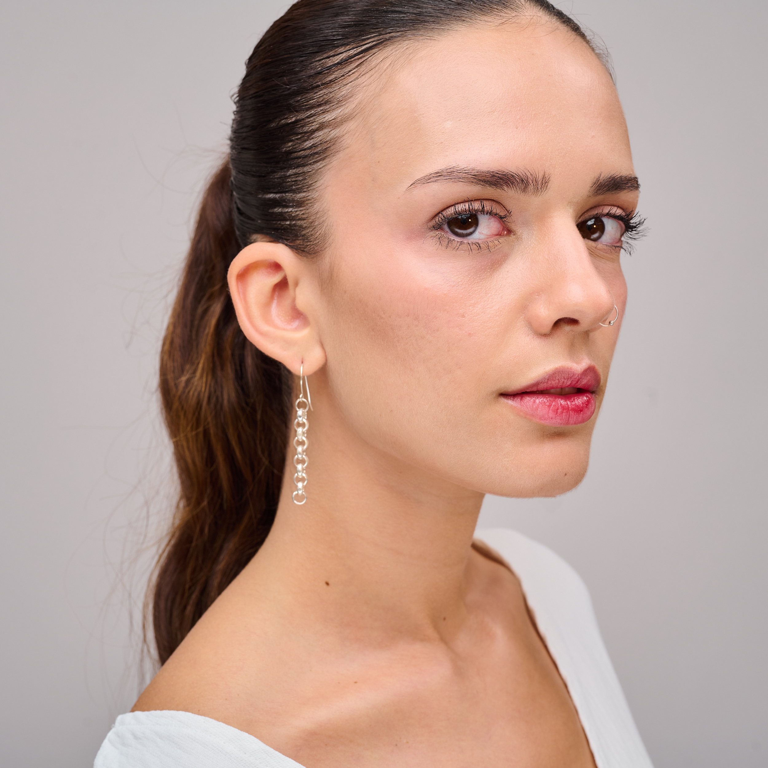 עגילים בעיצוב נקי ומוארך עשויים משרשרת כסף איכותית. השילוב בין הפשטות לעדינות יוצר תכשיט אלגנטי עם נוכחות מחמיאה לפנים. מושלם ללבישה יומיומית או כהשלמה למראה ערב. עיצוב ללא אבנים, מדגיש את יופיו הטבעי של הכסף.

