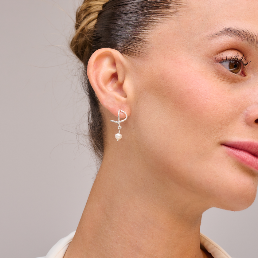 עגילים מכסף סטרלינג 925 עם פנינה לבנה במראה אלגנטי ונשי. עיצוב העגיל משלב בין קווים רכים לבין נוכחות בוהקת של הפנינה, מה שיוצר תכשיט שקט ומדויק. מתאימים ללבישה יומיומית, לערב חגיגי או כמתנה מרגשת לאישה שאוהבת יופי על-זמני. פנינים הן בחירה קלאסית שתמיד נכונה.

