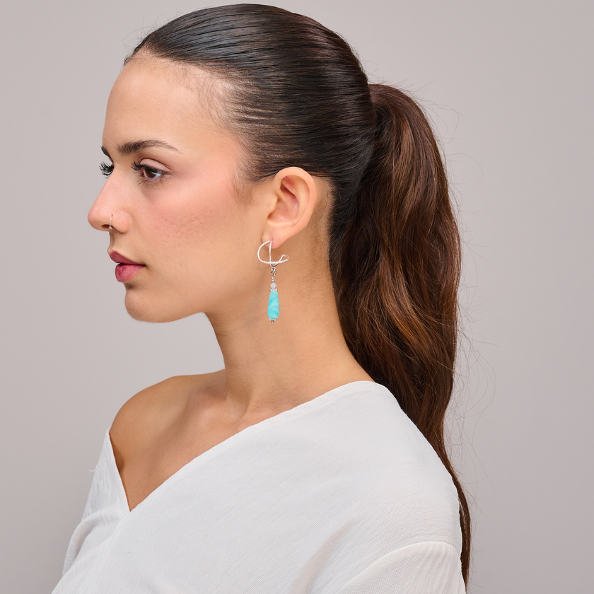 עגילי כסף בעבודת יד עם אמזונייט בגוון ירוק-כחול רך – תכשיט שמשלב אנרגיה מרגיעה עם עיצוב אלגנטי ונשי. אבן האמזונייט ידועה כאבן של שלווה, איזון וביטוי רגשי, ומשדרת תחושת טבע והרמוניה. העיצוב המעודן מתאים ליום-יום ולערב, עם נוכחות שקטה ונעימה. מתנה מושלמת לאישה שמחפשת תכשיט עם עומק פנימי וסטייל עדין.

