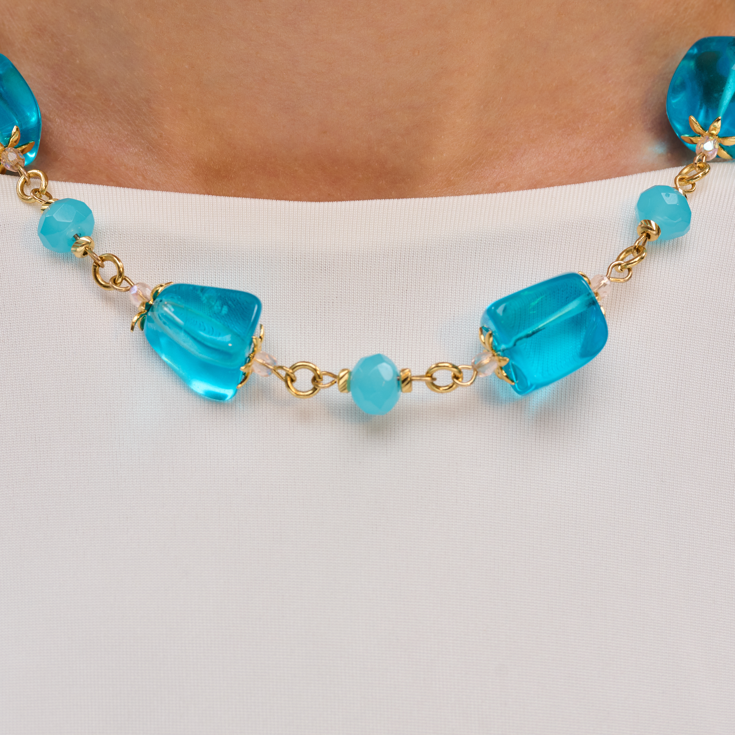 שרשרת צבעונית עם חרוזים כחולים בוהקים, בצורות מגוונות, ושילוב חלקי מתכת זהובים. תכשיט מלא שמחה, קייצי ובעל נוכחות, שמתאים ללבישה עם שמלה לבנה או כל לוק חופשי אך מוקפד.