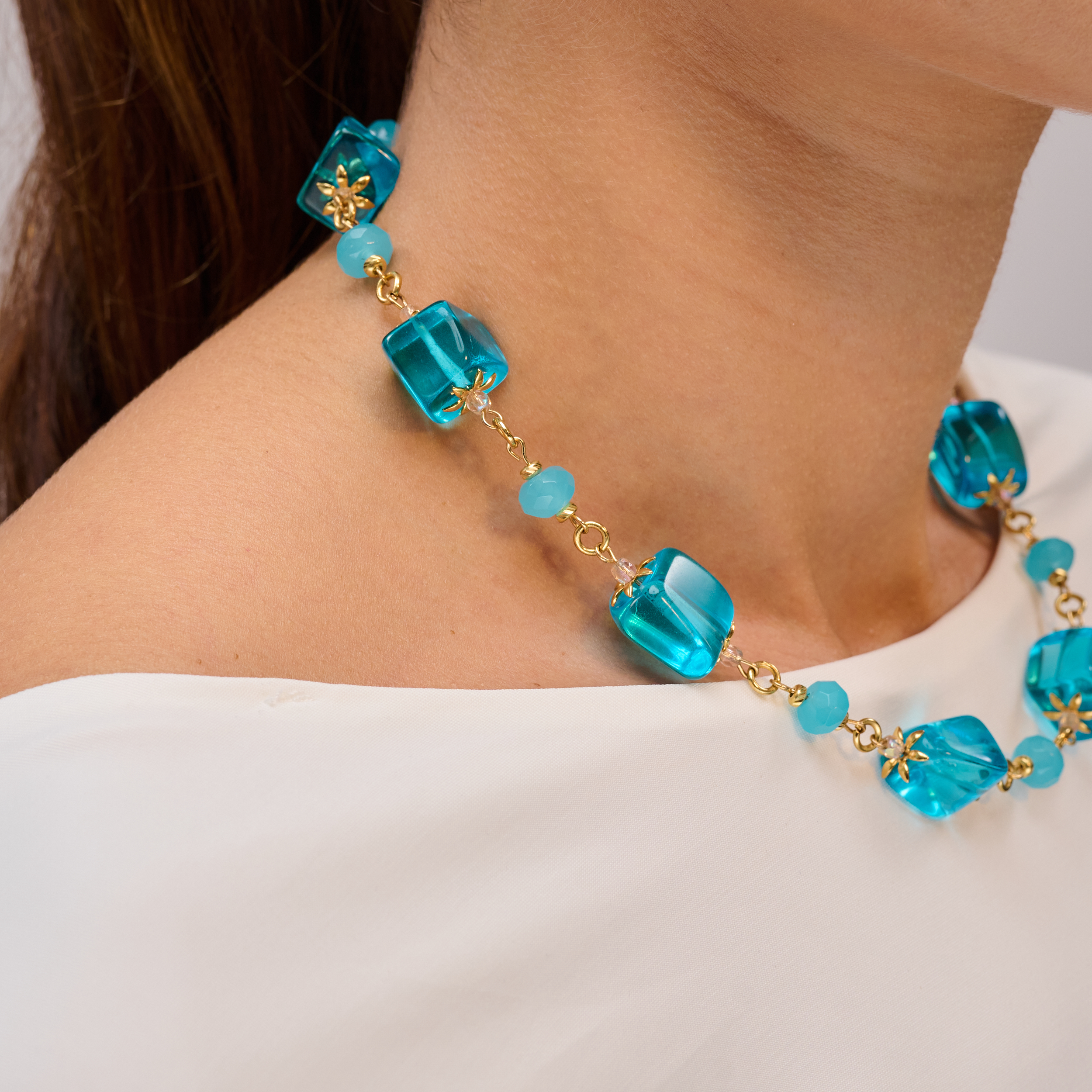 שרשרת בגווני כחול ים בעיצוב דינמי עם קוביות זכוכית ונגיעות זהב. קולר בעבודת יד שנראה כמו שילוב של אמנות מודרנית וטבע פראי – מושלם לכל חובבת תכשיטים שמחפשת אמירה.