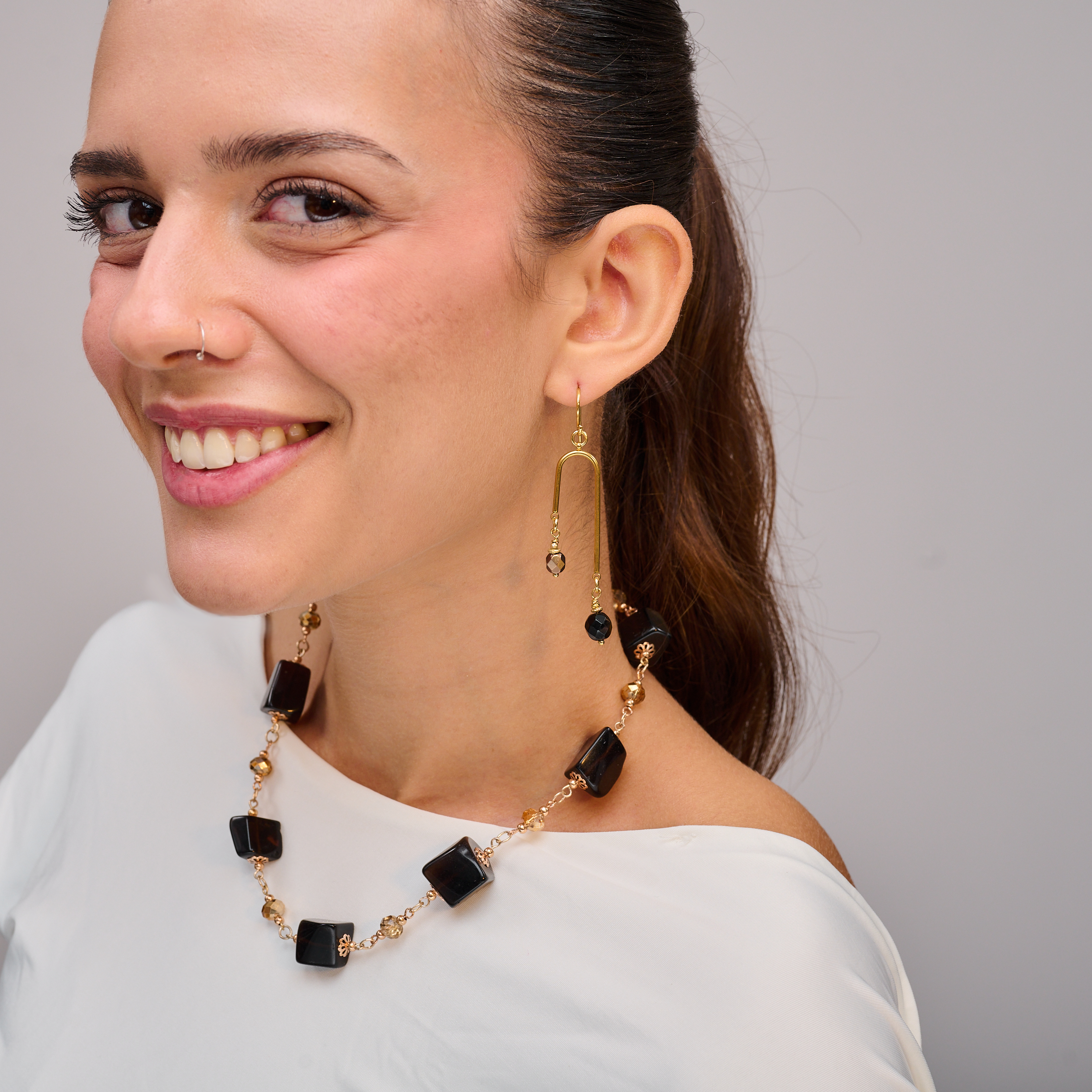 שרשרת אבנים בגוון שחור כהה, המשלבת צורות שונות – עגולות, פחוסות, גיאומטריות – ליצירת קומפוזיציה ייחודית עם זרימה חופשית. צבע אחיד אך עם נוכחות טקסטורלית. תכשיט שמרגיש כמו הצהרה אופנתית שקטה ומלאת עומק.

