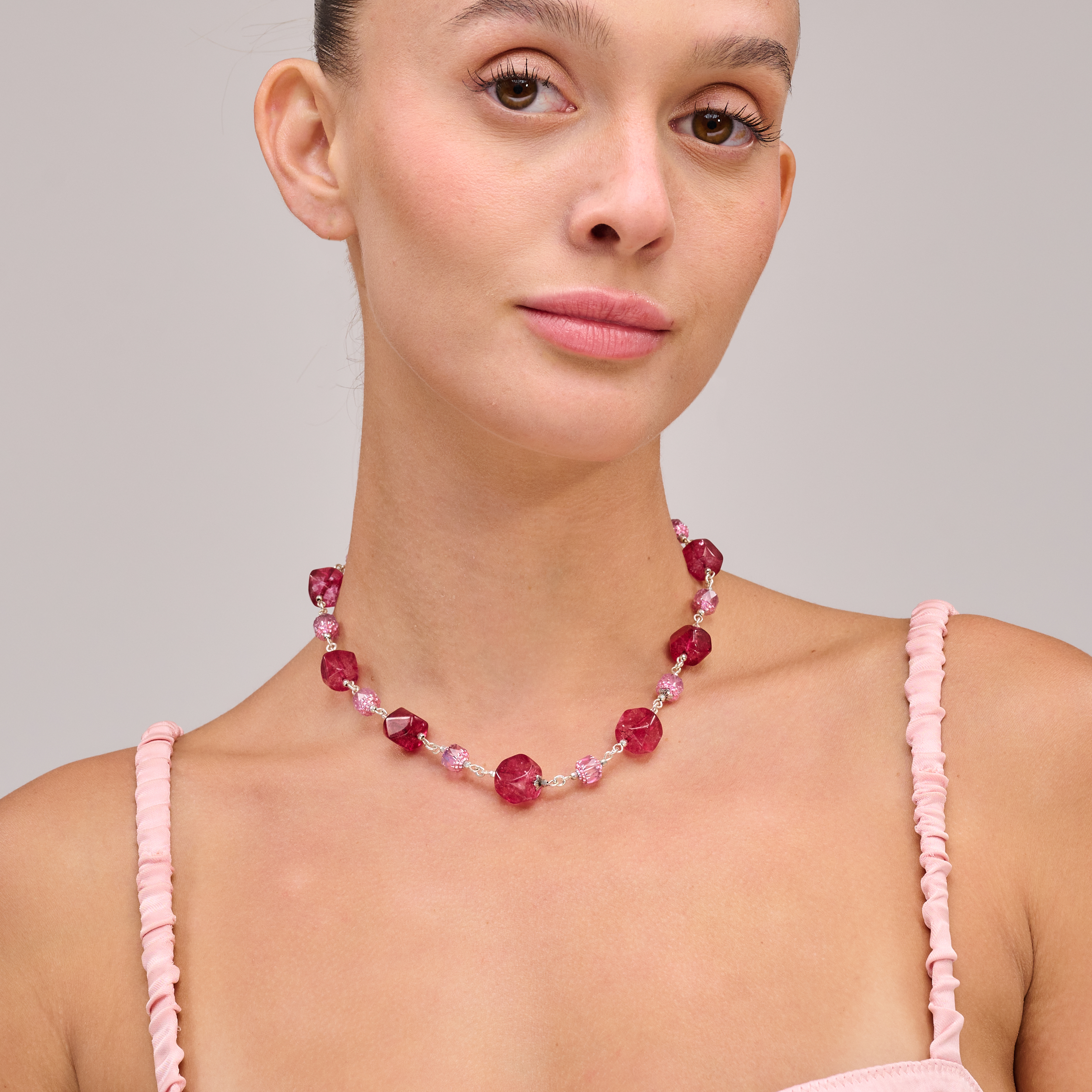 שרשרת ייחודית בעבודת יד, משובצת באבנים בגווני ורוד עדין ובורדו עמוק, יוצרת מראה עשיר, נשי ואלגנטי. האבנים נעות בין גווני פודרה רכים לבין צבעי יין חמים, עם ברק טבעי מרהיב. כל אבן נבחרה בקפידה ומשולבת בקומפוזיציה מדויקת ליצירת ניגוד הרמוני – בין רכות לתשוקה, בין אור לשקיעה. תכשיט מלא אופי שמתאים לאירוע ערב, למראה חגיגי אך גם כהשלמה מרשימה ליום-יום. מושלם כמתנה למישהי עם סגנון אישי חזק ורך בו זמנית.