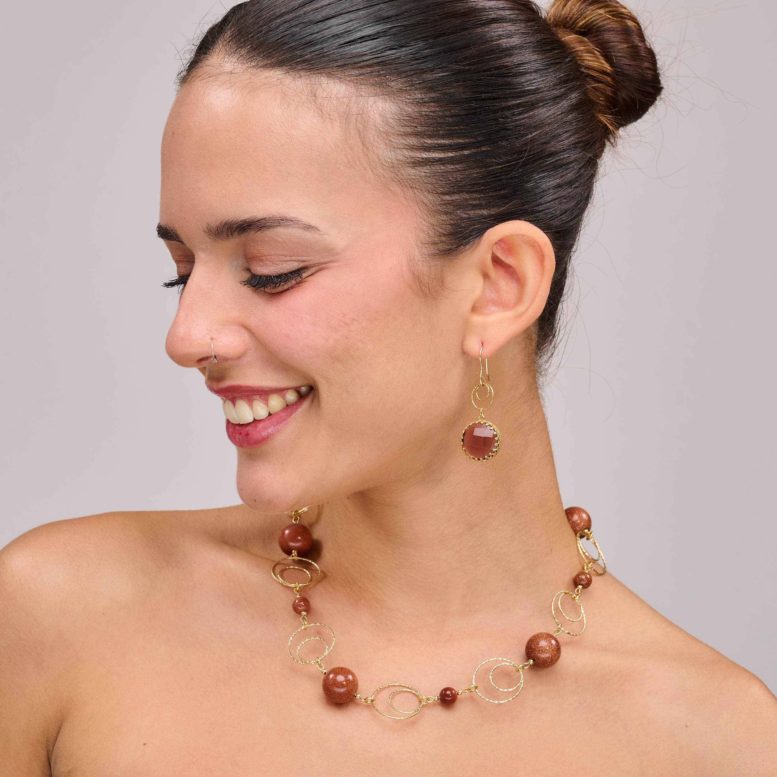 שרשרת בגווני חום־זהוב עם אבני אוונטיורין טבעיות, בעלות ברק עדין וגוון חם במיוחד. האבנים יוצרות תחושת חיבוק עוטף סביב הצוואר, ומשדרות אנרגיה של שלווה, קרקוע ונשיות. עיצוב שמתאים למראה קז'ואלי עם טוויסט או כאביזר מרכזי בהופעה אלגנטית עם קווים נקיים. לכל אבן אופי משלה – מה שהופך את השרשרת לייחודית, ממש כמו מי שעונדת אותה.