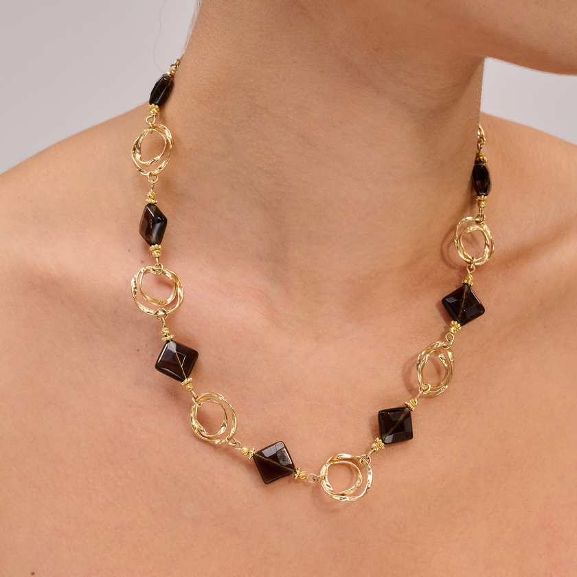 שרשרת בגוונים עמוקים של טופז חום – אבן טבעית המהדהדת יציבות, חמימות ועוצמה רגועה. כל אבן משולבת עם אלמנטים מצופי זהב, מעובדים בעבודת יד מוקפדת המוסיפה גימור קלאסי ומגע של יוקרה. תכשיט עם נוכחות עדינה אך יוקרתית, המתאים להופעות עם עומק וסטייל אישי לא מתאמץ.

