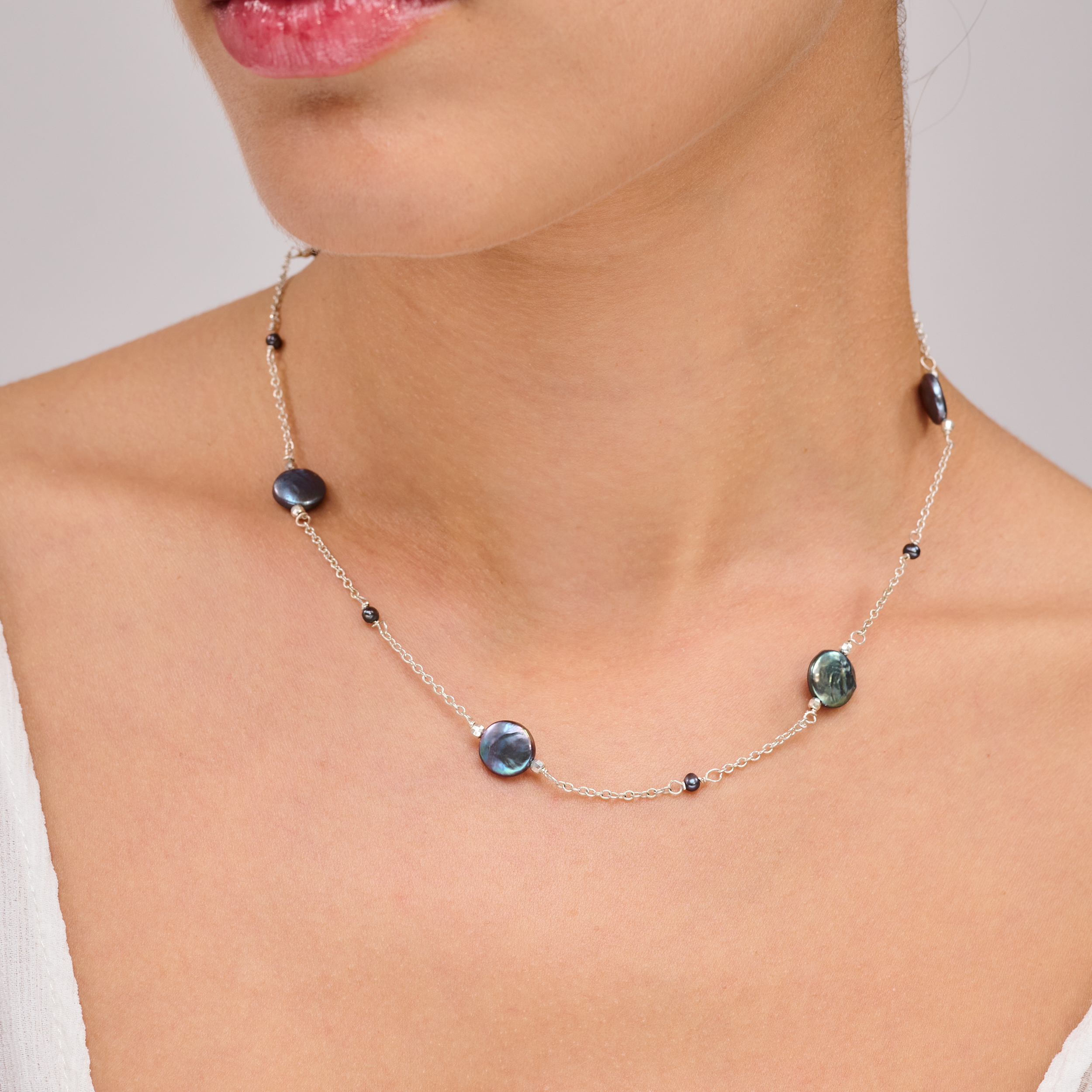 תכשיט כסף עם פניני טהיטי בגוון עשיר – תכשיט אלגנטי ונקי, שמשלב מראה מודרני עם עומק צבע טבעי. הפנינים העגולות בגוון אפור־כחלחל כהה משתלבות על גבי שרשרת כסף עדינה ומוסיפות לה אור עמוק עם אפקט מסתורי. העיצוב עיצוב עכשווי עם גישה על־זמנית – מתאים לנשים שמעדיפות תכשיטים מתוחכמים שאינם צועקים אך אי אפשר להתעלם מהם. השרשרת מושלמת ללבישה יומיומית אלגנטית או כפריט שמשתלב בקלות במראה ערב או לוק קלאסי יומיומי.