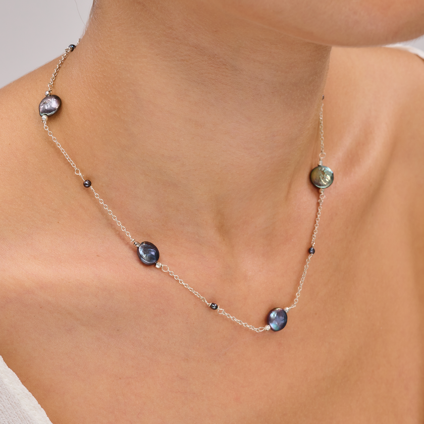 תכשיט כסף עם פניני טהיטי בגוון עשיר – תכשיט אלגנטי ונקי, שמשלב מראה מודרני עם עומק צבע טבעי. הפנינים העגולות בגוון אפור־כחלחל כהה משתלבות על גבי שרשרת כסף עדינה ומוסיפות לה אור עמוק עם אפקט מסתורי. העיצוב עיצוב עכשווי עם גישה על־זמנית – מתאים לנשים שמעדיפות תכשיטים מתוחכמים שאינם צועקים אך אי אפשר להתעלם מהם. השרשרת מושלמת ללבישה יומיומית אלגנטית או כשרשרת שמשלימה הופעה עם טעם טוב ועדינות.