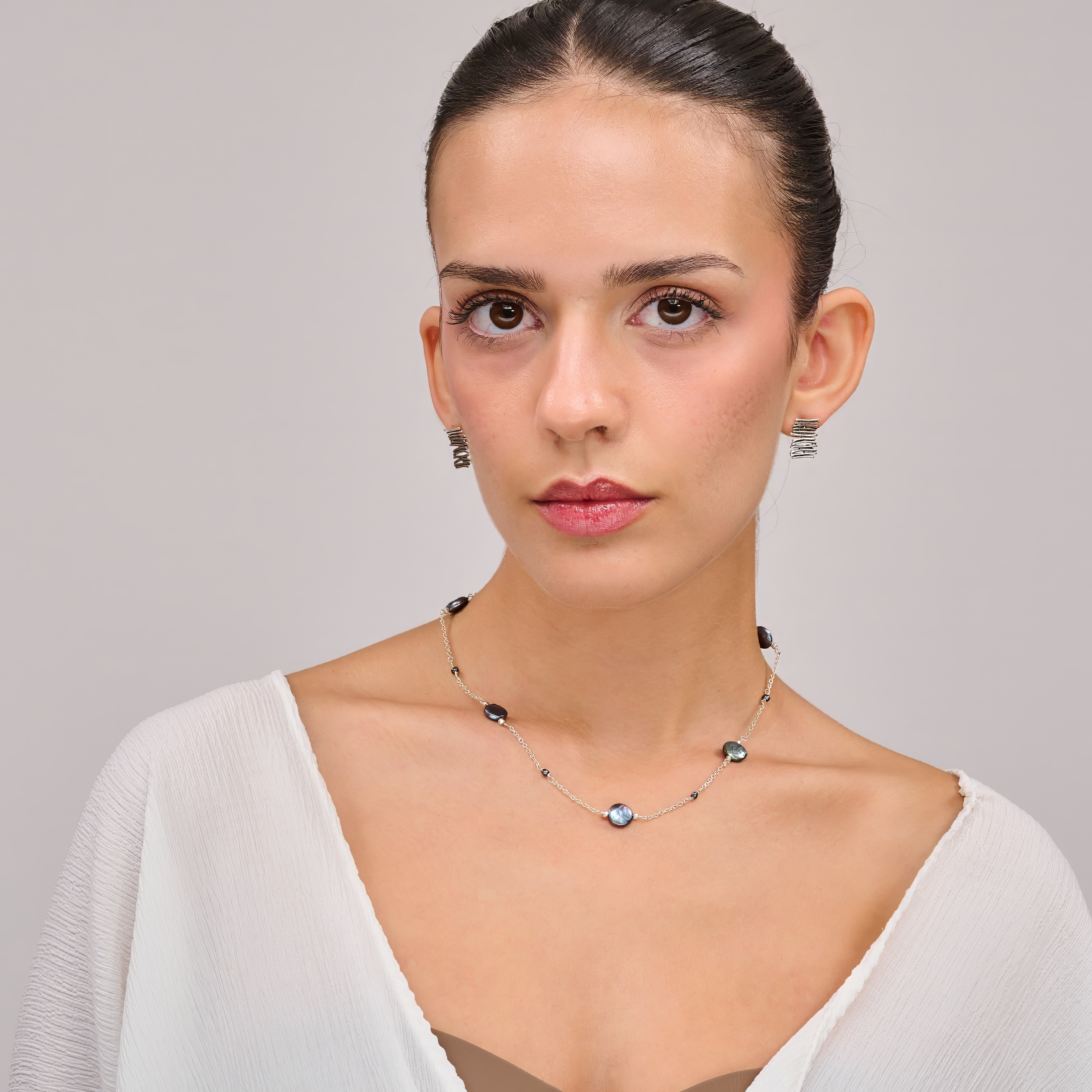 שרשרת מודרנית מכסף עם פנינים כהות טבעיות – תכשיט אלגנטי ונקי, שמשלב מראה מודרני עם עומק צבע טבעי. הפנינים העגולות בגוון אפור־כחלחל כהה משתלבות על גבי שרשרת כסף עדינה ומוסיפות לה נגיעה של יוקרה רגועה. העיצוב עיצוב עכשווי עם גישה על־זמנית – מתאים לנשים שמעדיפות תכשיטים מתוחכמים שאינם צועקים אך אי אפשר להתעלם מהם. השרשרת מושלמת ללבישה יומיומית אלגנטית או כבחירה מושלמת לנשים שמחפשות מראה מאוזן ואלגנטי.
העגילים להמחשה בלבד